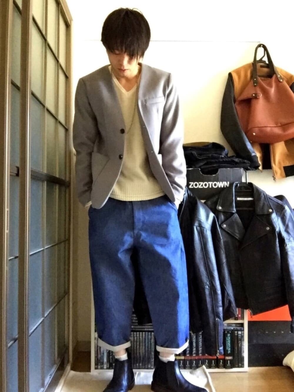 グレー系のテーラードジャケット、ベージュ系のニット/セーター、ブルー系のデニムパンツを着用したメンズの冬コーディネートの1枚目の写真