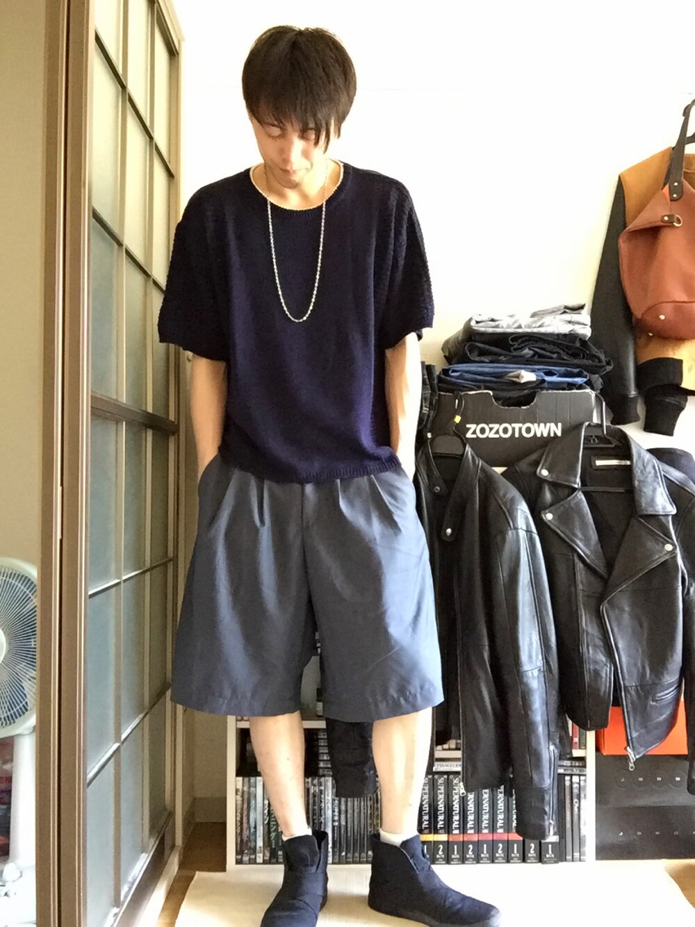 ブルー系のニット/セーター、グレー系のスラックス、ブラック系のスニーカーを着用したメンズの春コーディネートの1枚目の写真