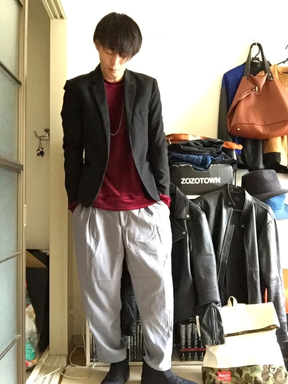 ブラック系のテーラードジャケット、レッド系のTシャツ/カットソー、グレー系のスラックスを着用したメンズの秋コーディネートの1枚目の写真