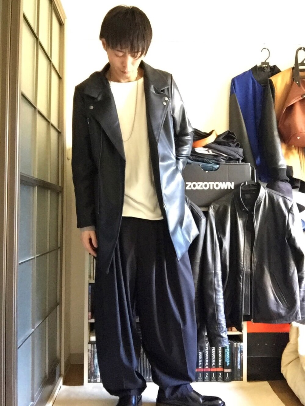 ブラック系のライダースジャケット、ホワイト系のニット/セーター、ブラック系のスラックスを着用したメンズの秋コーディネートの1枚目の写真