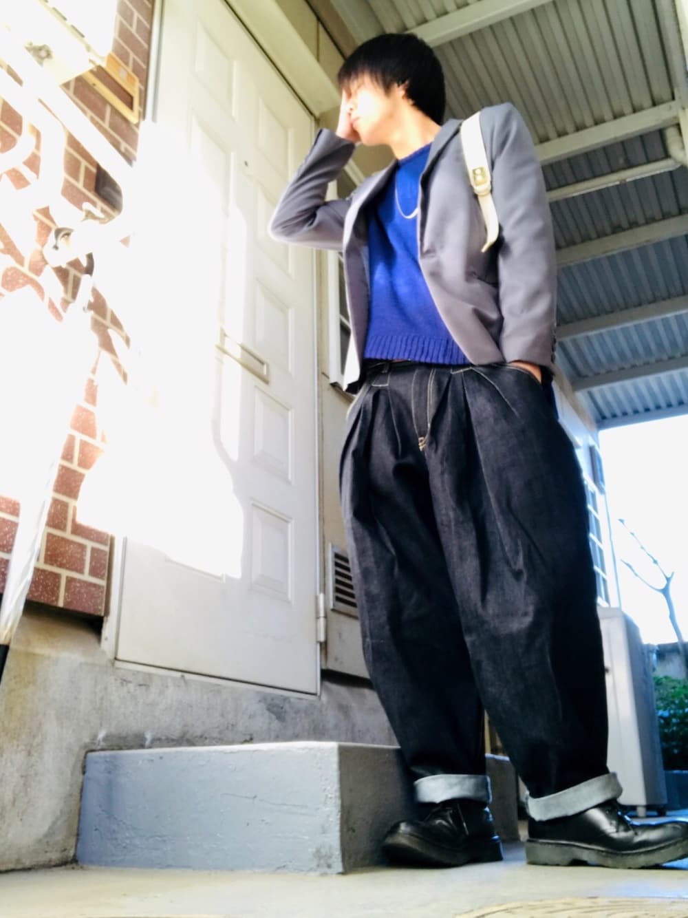 グレー系のテーラードジャケット、ブルー系のニット/セーター、ブルー系のデニムパンツを着用したメンズの冬コーディネートの1枚目の写真