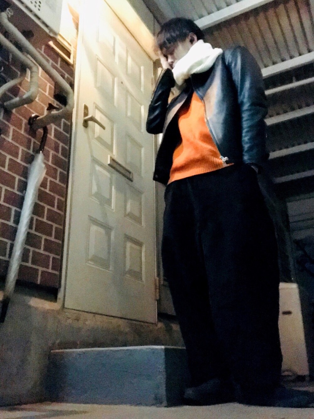 ブラック系のライダースジャケット、オレンジ系のニット/セーター、ブラック系のその他パンツを着用したメンズの冬コーディネートの1枚目の写真