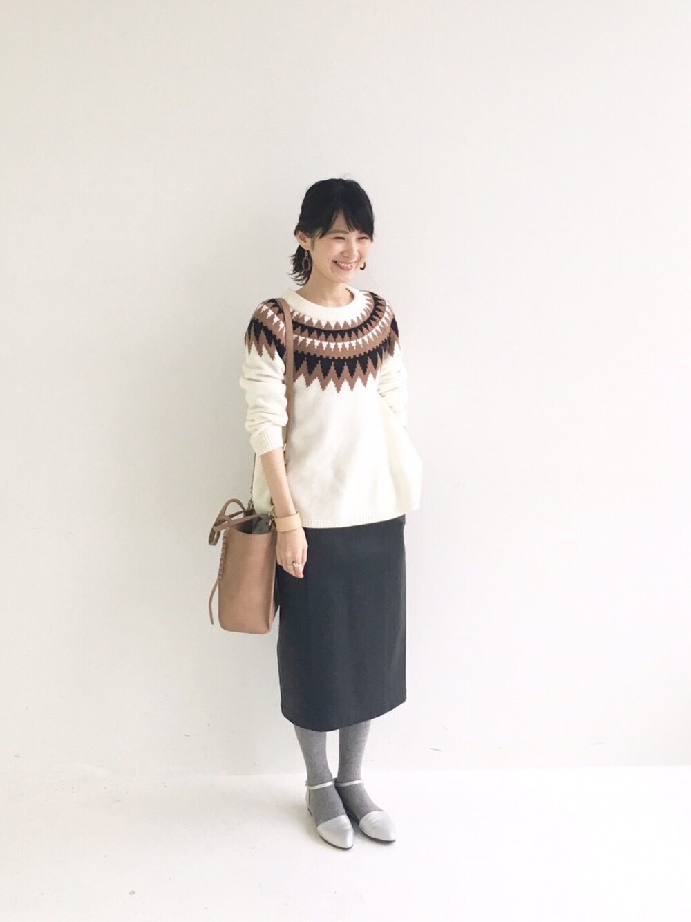 ホワイト系のニット/セーター、ブラック系のスカート、シルバー系のパンプスを着用したレディースの冬コーディネートの1枚目の写真