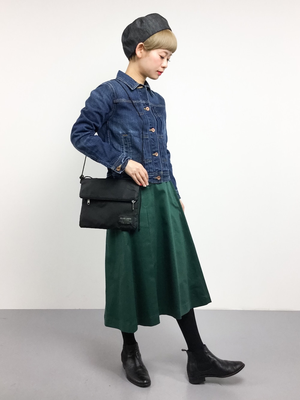 グリーン系のスカート、ブルー系のデニムジャケット、ブラック系のショルダーバッグを着用したレディースの春コーディネートの1枚目の写真