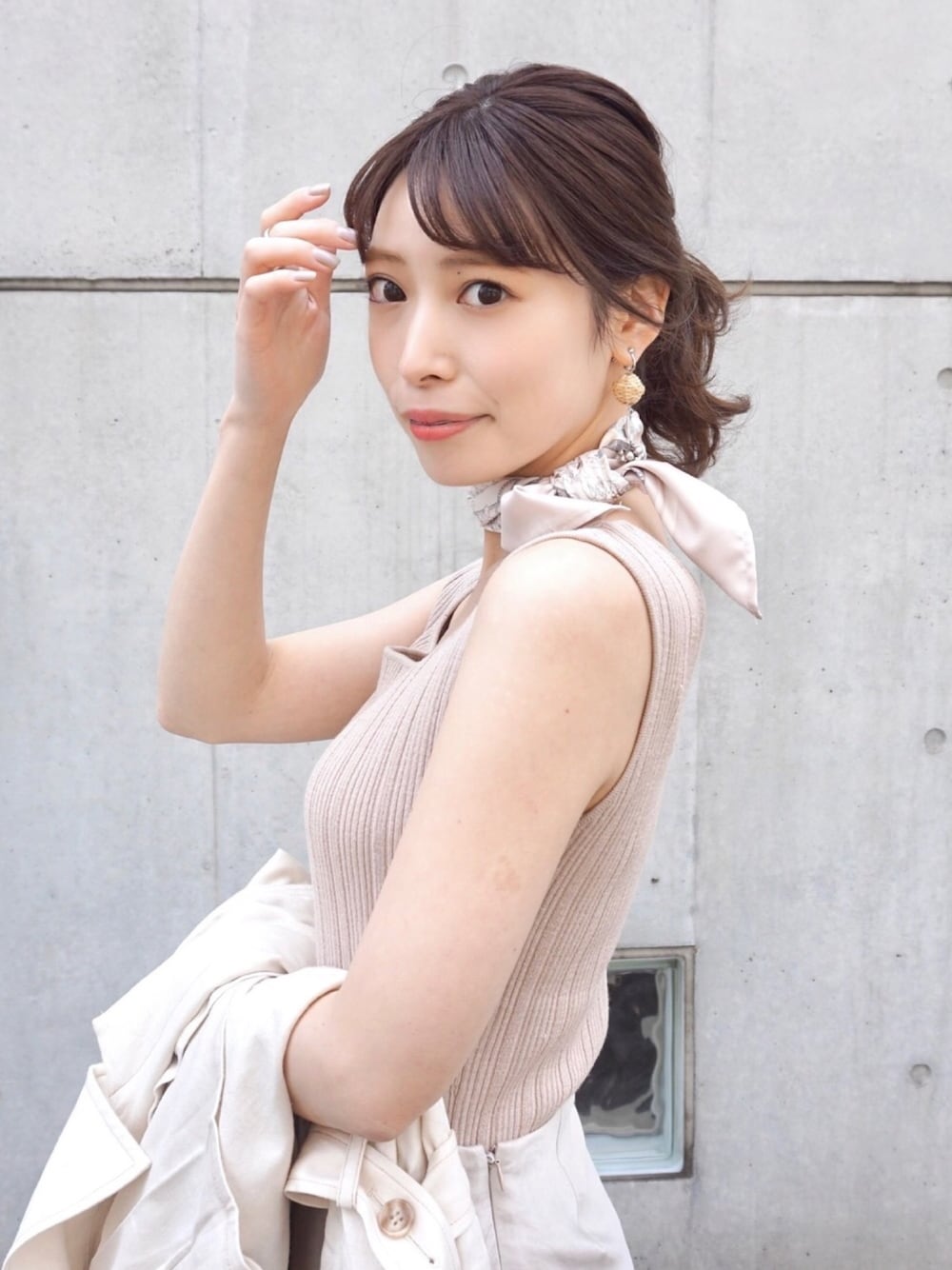 ベージュ系のニット/セーター、ホワイト系のステンカラーコート、その他のイヤリングを着用したレディースの春コーディネートの1枚目の写真