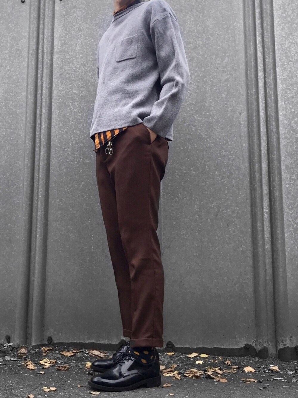 イエロー系のシャツ/ブラウス、グレー系のニット/セーター、ブラウン系のスラックスを着用したメンズの秋コーディネートの1枚目の写真