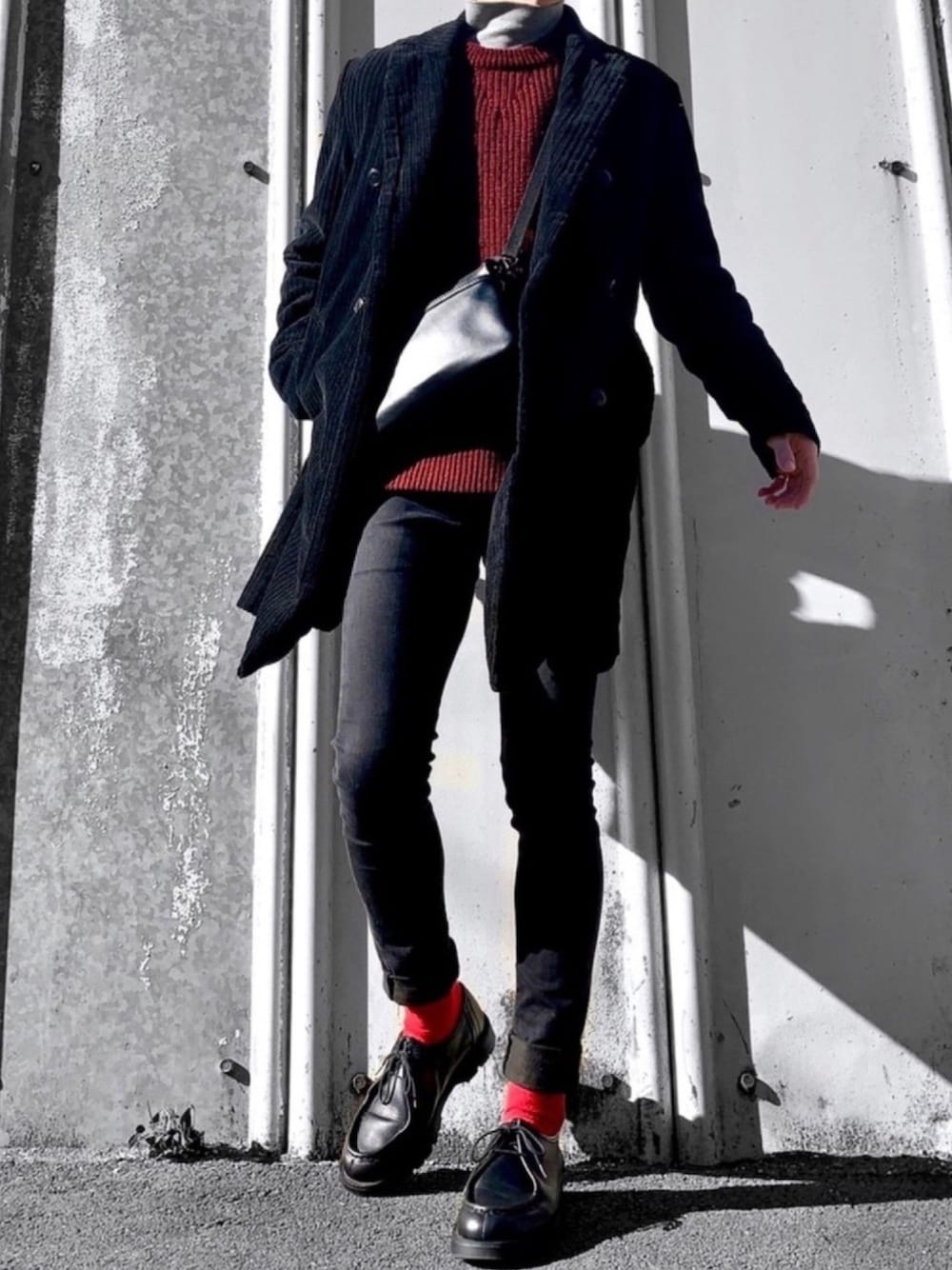 レッド系のニット/セーター、ブラック系のチェスターコート、ブラック系のショルダーバッグを着用したメンズの冬コーディネートの1枚目の写真