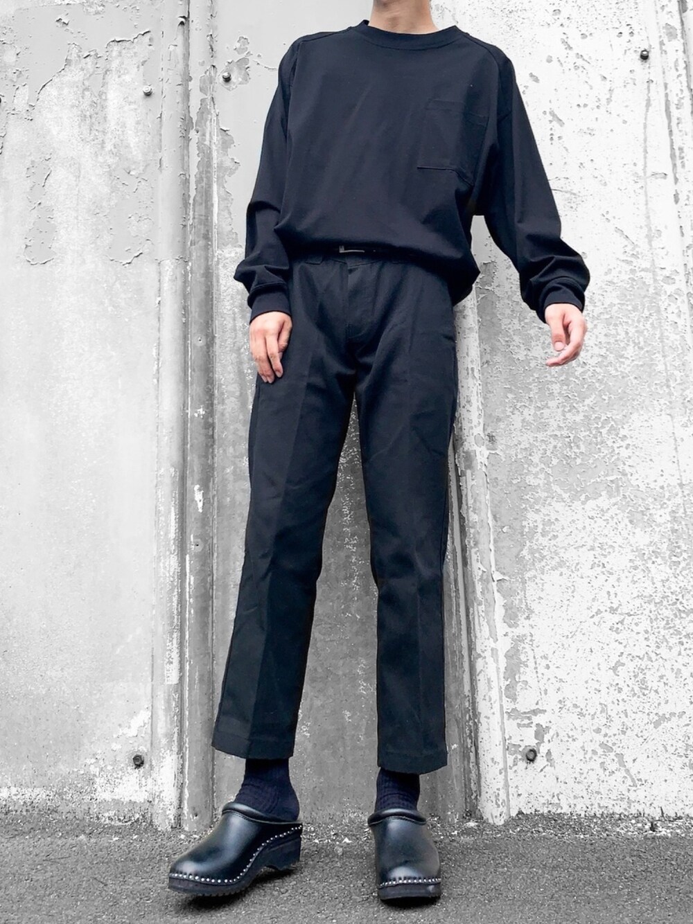 ブラック系のTシャツ/カットソー、ブラック系のチノパンツ、ブラック系のサンダルを着用したメンズの秋コーディネートの1枚目の写真