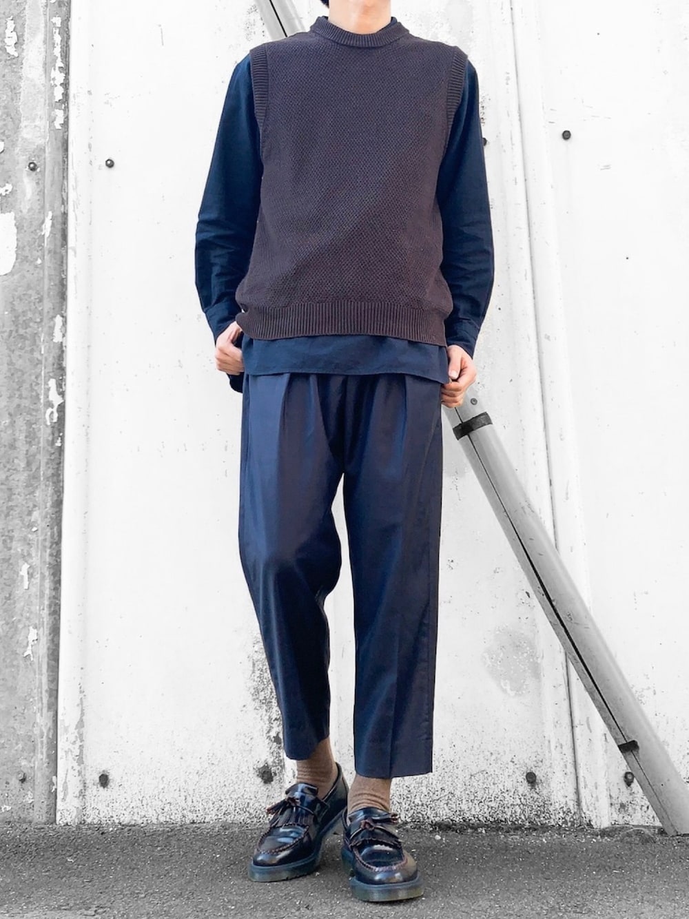 グレー系のニット/セーター、ブルー系のシャツ/ブラウス、ブルー系のスラックスを着用したメンズの秋コーディネートの1枚目の写真