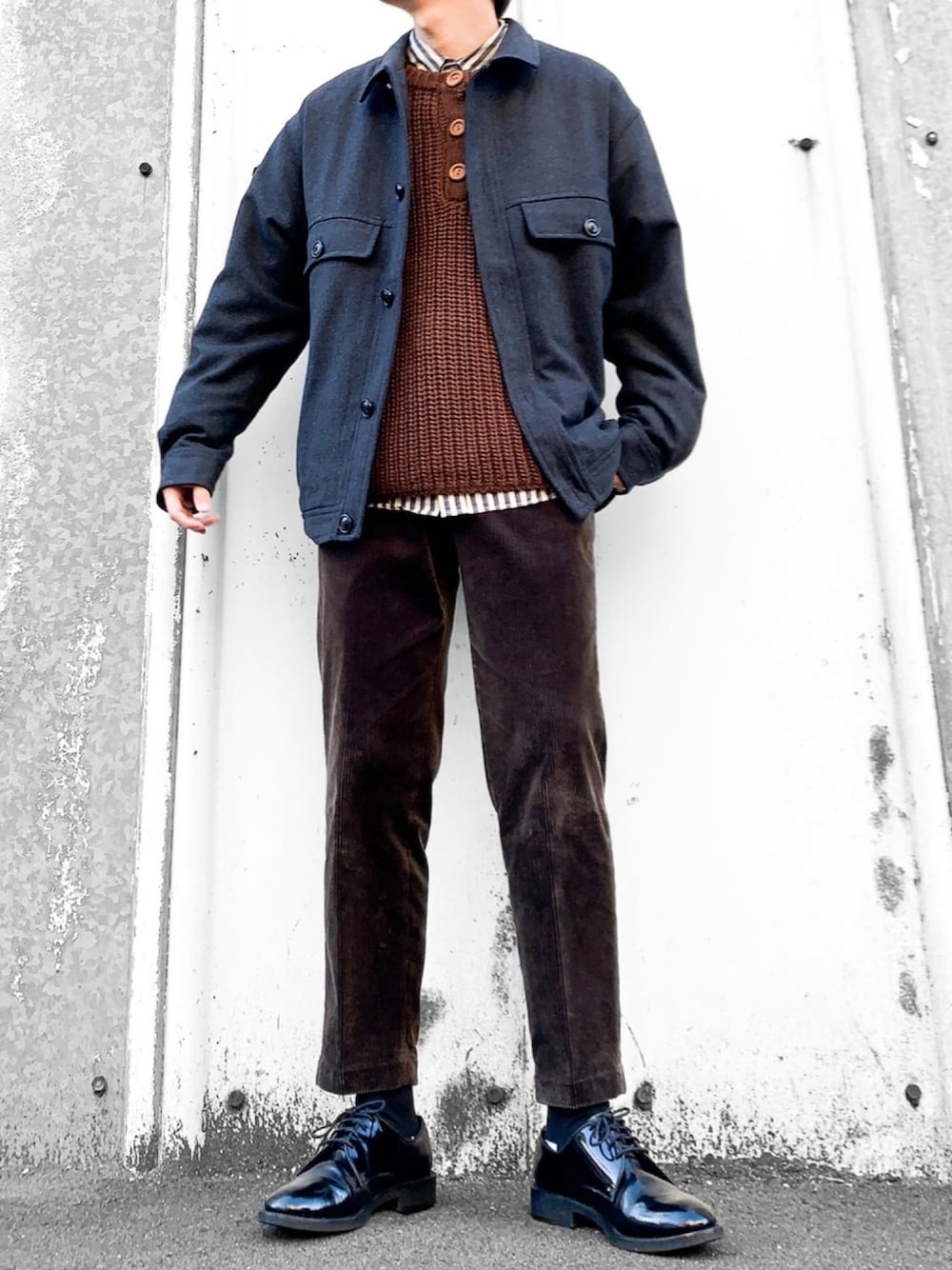 グレー系のミリタリージャケット、ブラウン系のニット/セーター、ホワイト系のシャツ/ブラウスを着用したメンズの冬コーディネートの1枚目の写真