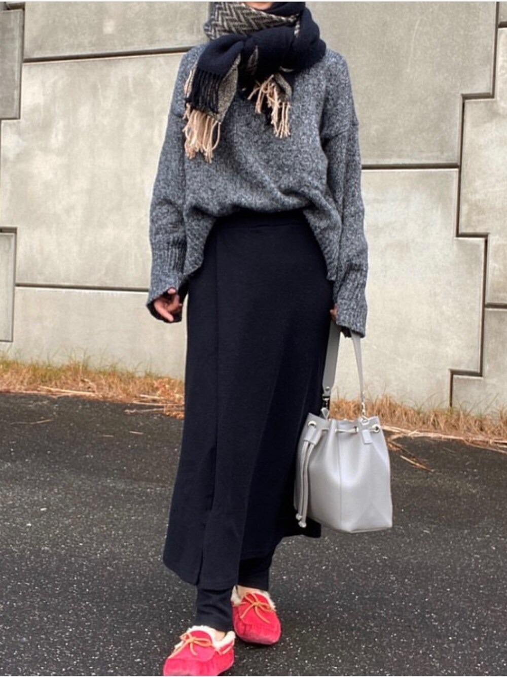 グレー系のニット/セーター、ブラック系のスカート、レッド系のモカシン/デッキシューズを着用したレディースの秋コーディネートの1枚目の写真