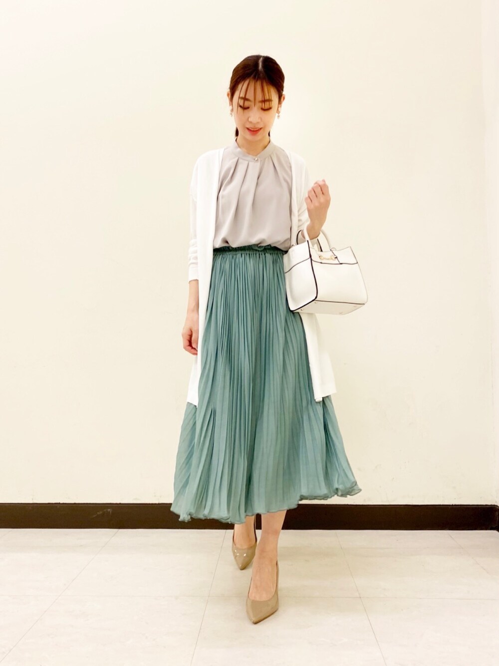 グリーン系のスカート、ベージュ系のパンプス、グレー系のシャツ/ブラウスを着用したレディースの春コーディネートの1枚目の写真