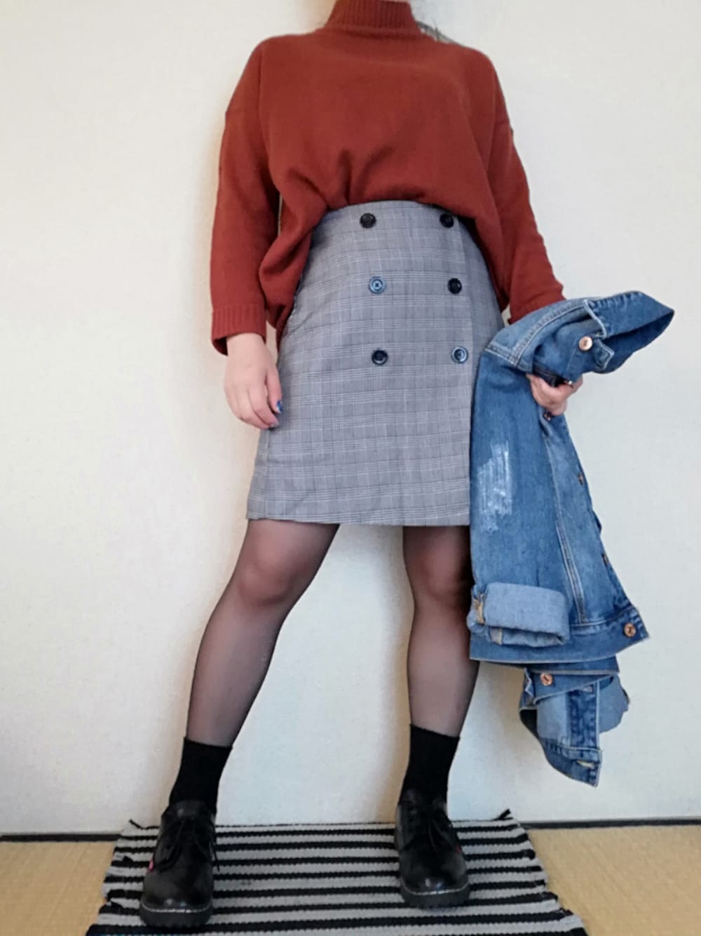 オレンジ系のニット/セーター、ブラック系のスカート、ブラック系のシューズを着用したレディースの秋コーディネートの1枚目の写真