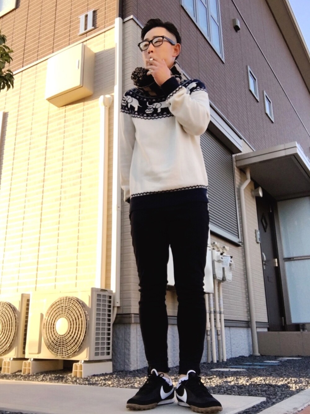 ブラック系のスラックス、ブラック系のスニーカー、ホワイト系のニット/セーターを着用したメンズの冬コーディネートの1枚目の写真