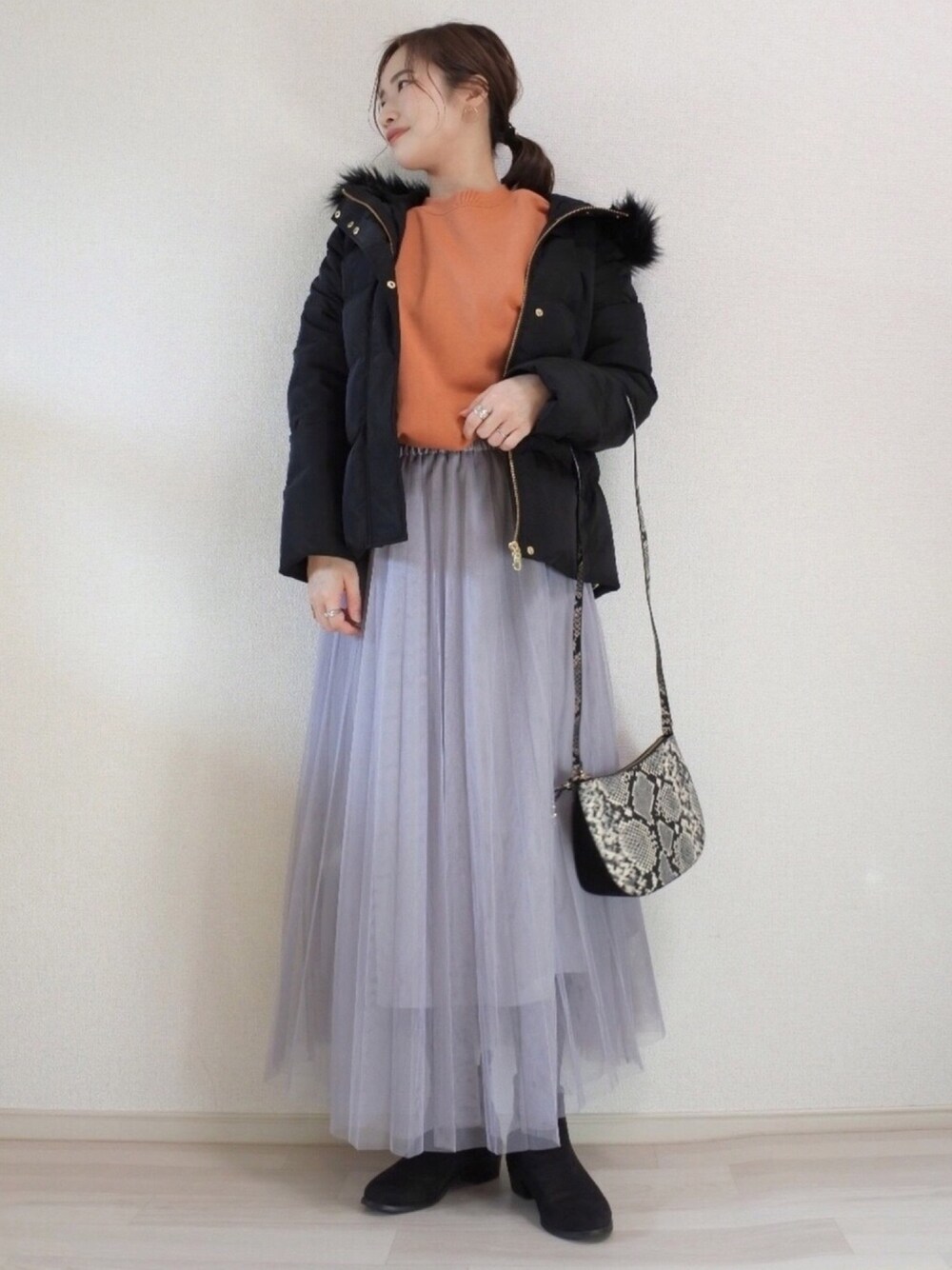 ブラック系のブーツ、オレンジ系のスウェット、グレー系のスカートを着用したレディースの冬コーディネートの1枚目の写真