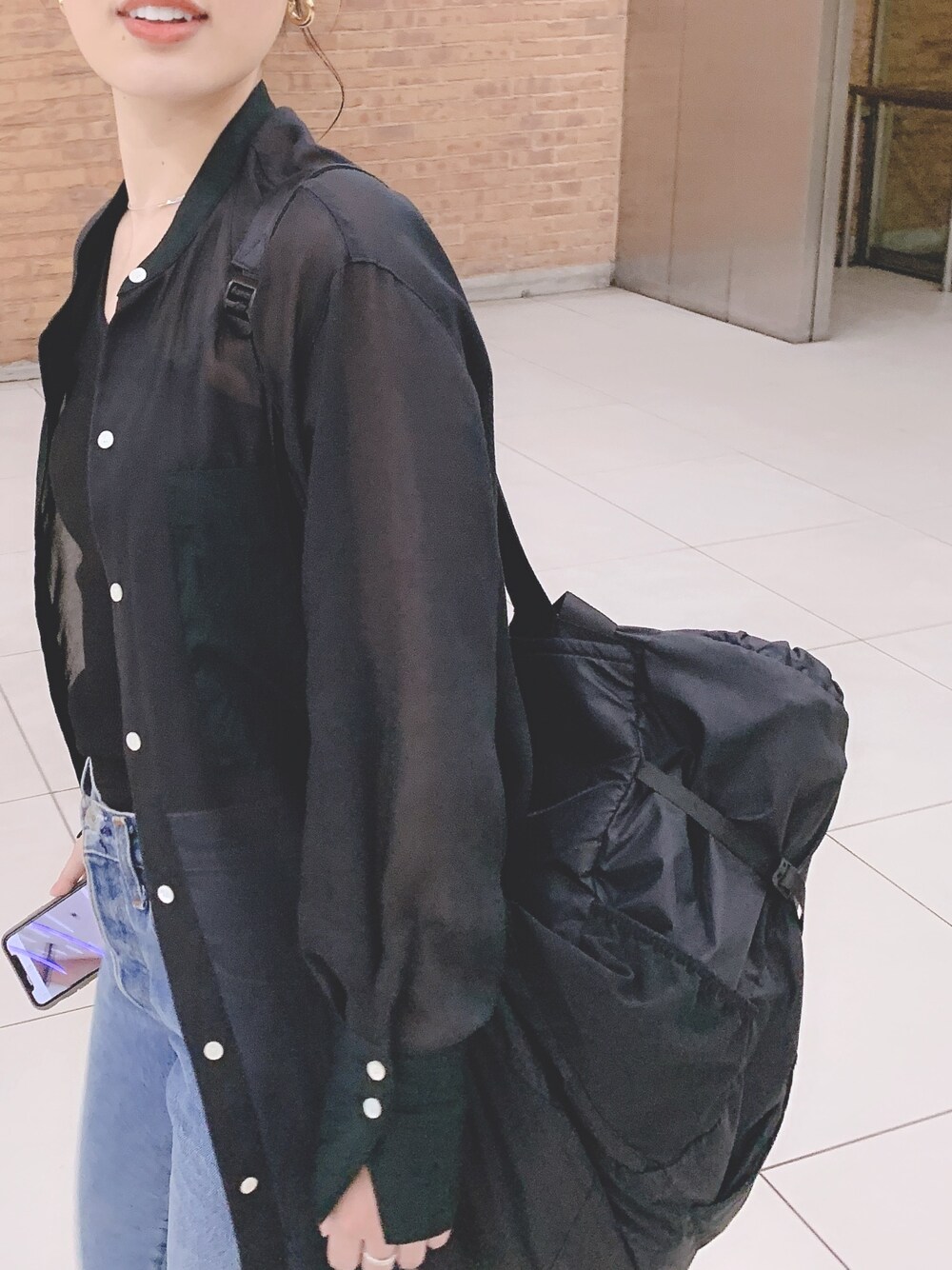 ブラック系のシャツ/ブラウス、ブルー系のデニムパンツ、ブラック系のバックパック/リュックを着用したレディースの夏コーディネートの1枚目の写真