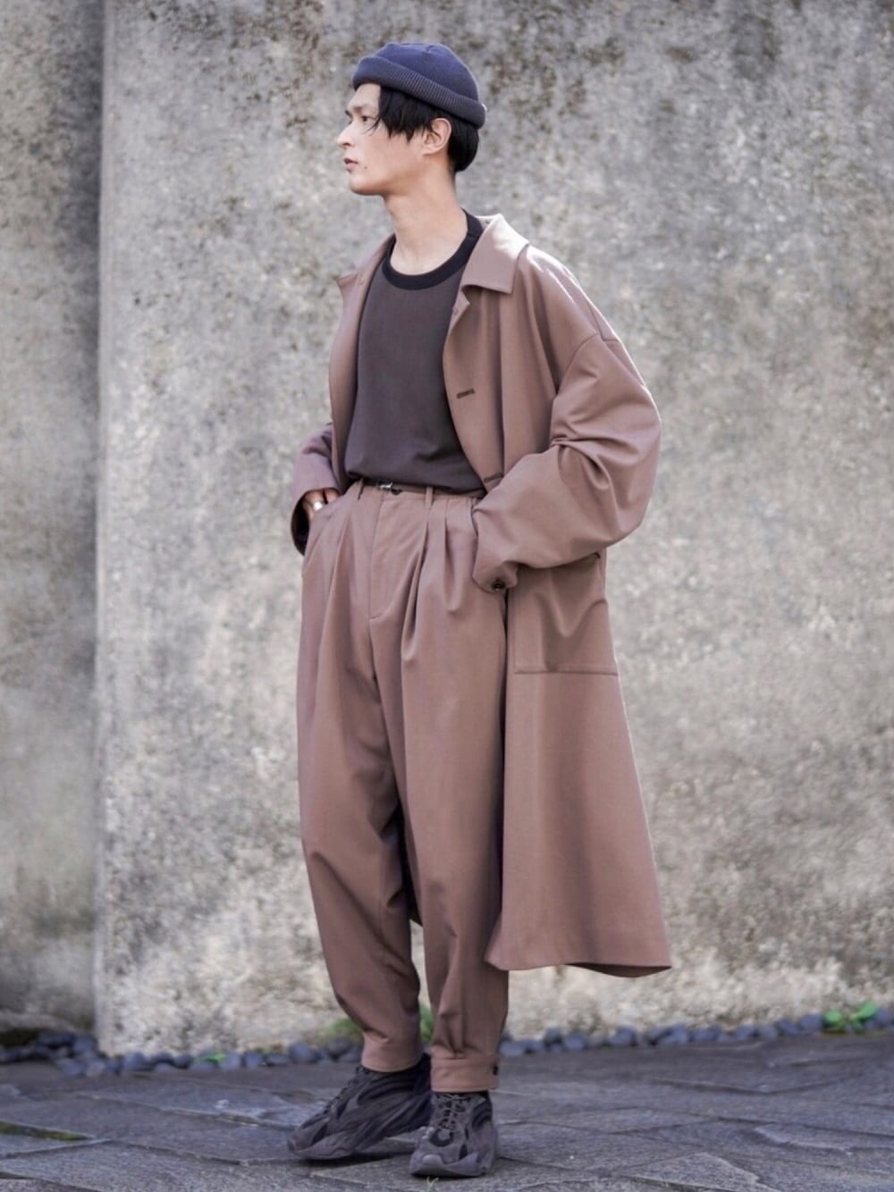 ブラウン系のステンカラーコート、ブラウン系のその他パンツ、ブラック系のTシャツ/カットソーを着用したメンズの秋コーディネートの1枚目の写真