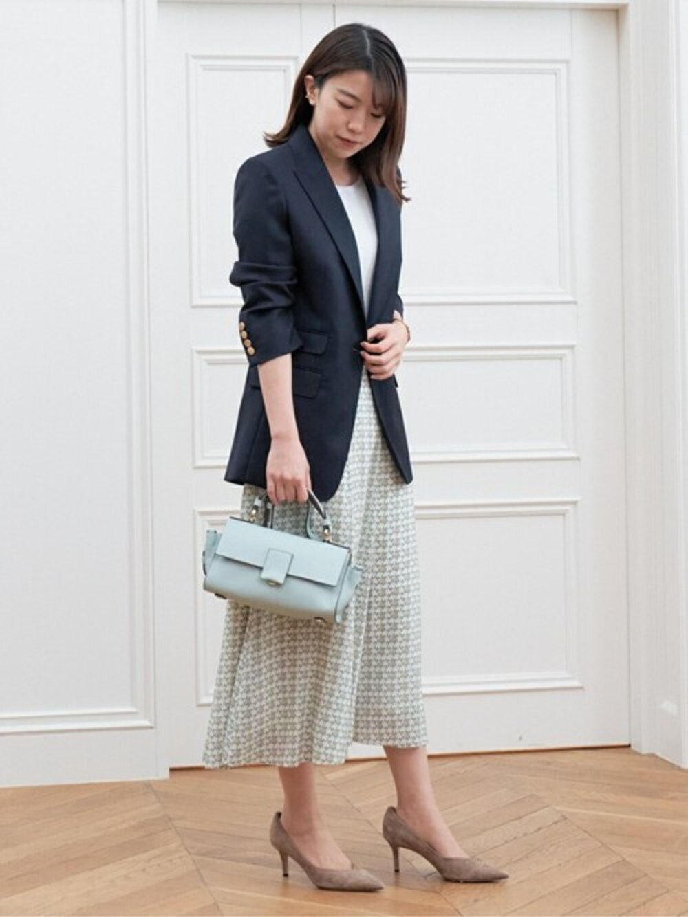 ホワイト系のニット/セーター、ベージュ系のスカート、グリーン系のハンドバッグを着用したレディースの夏コーディネートの1枚目の写真