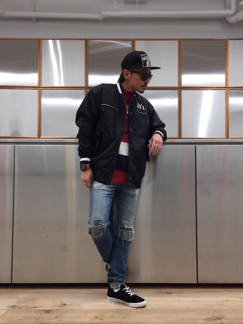 ブルー系のデニムパンツ、ブラック系のスタジャン、レッド系のスウェットを着用したメンズの春コーディネートの1枚目の写真