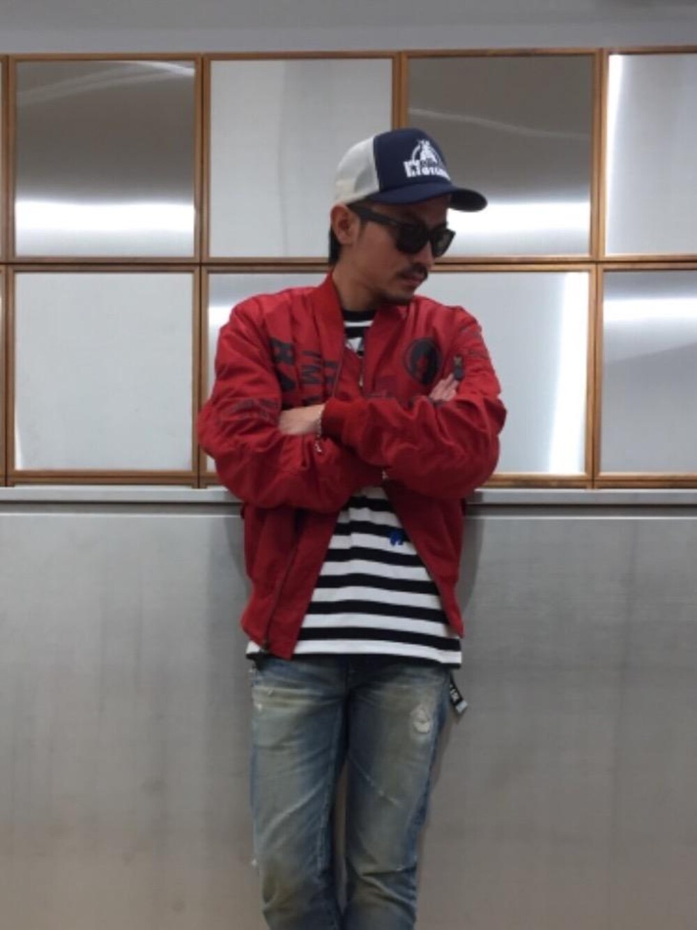 ブラック系のTシャツ/カットソー、ブルー系のデニムパンツ、レッド系のミリタリージャケットを着用したメンズの秋コーディネートの1枚目の写真