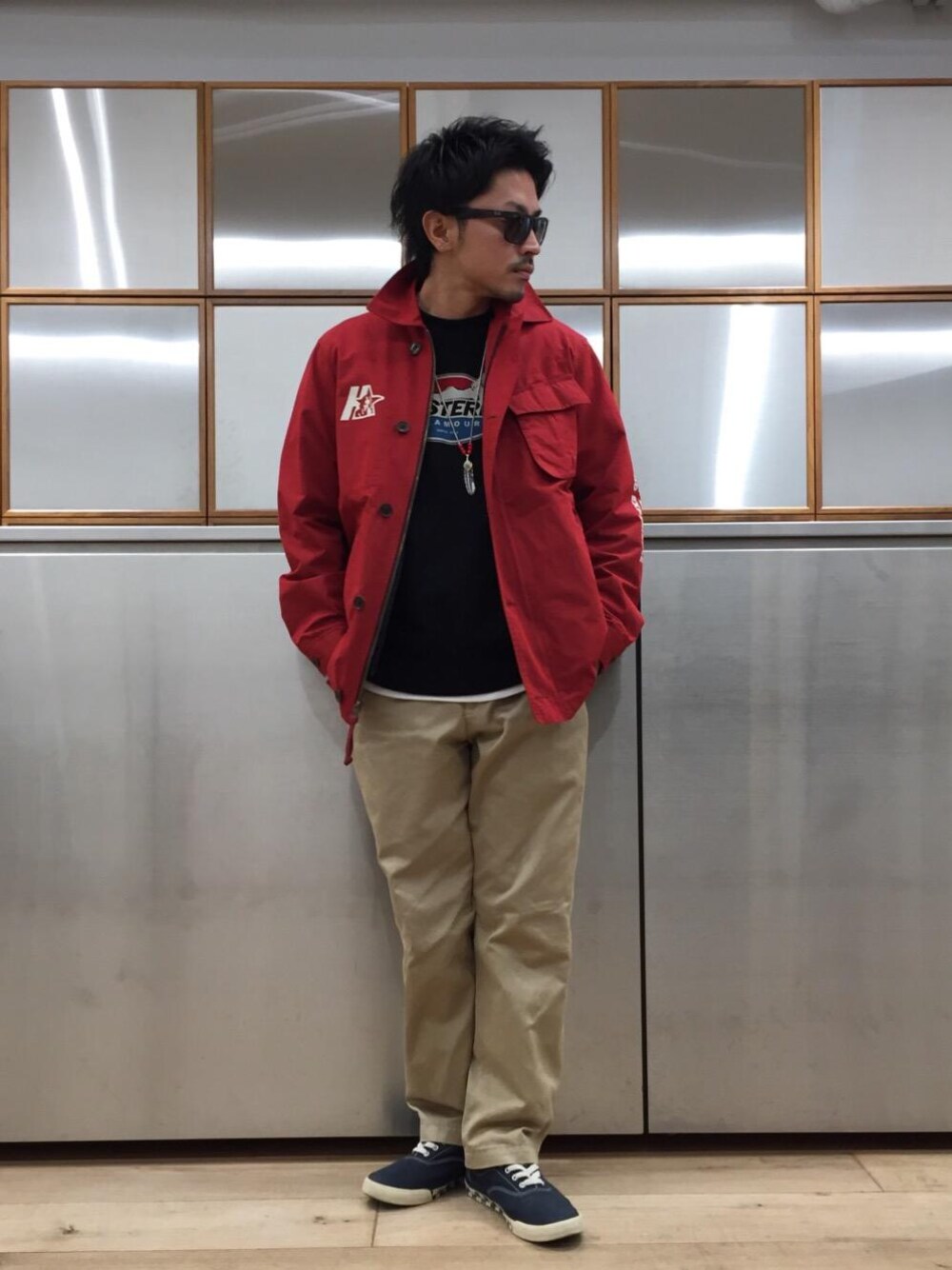 ベージュ系のチノパンツ、ブラック系のスウェット、レッド系のミリタリージャケットを着用したメンズの冬コーディネートの1枚目の写真