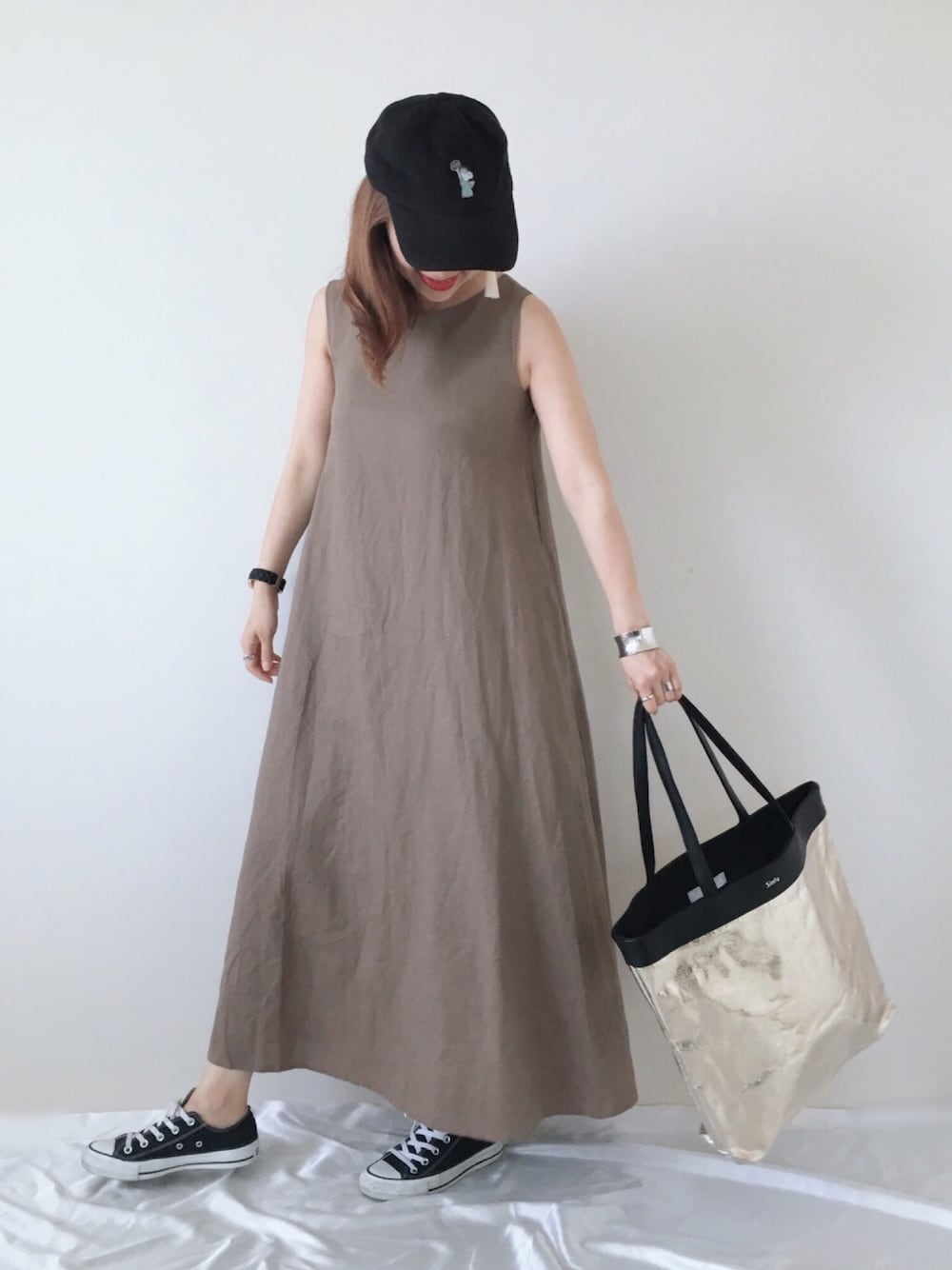 ブラウン系のワンピース、ゴールド系のトートバッグ、ブラック系のスニーカーを着用したレディースの夏コーディネートの1枚目の写真