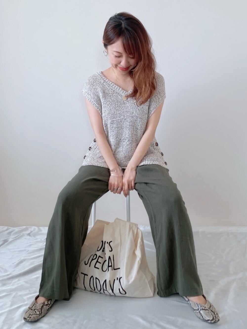 ブラウン系のTシャツ/カットソー、グリーン系のパンツ、ホワイト系のエコバッグ/サブバッグを着用したレディースの春コーディネートの1枚目の写真