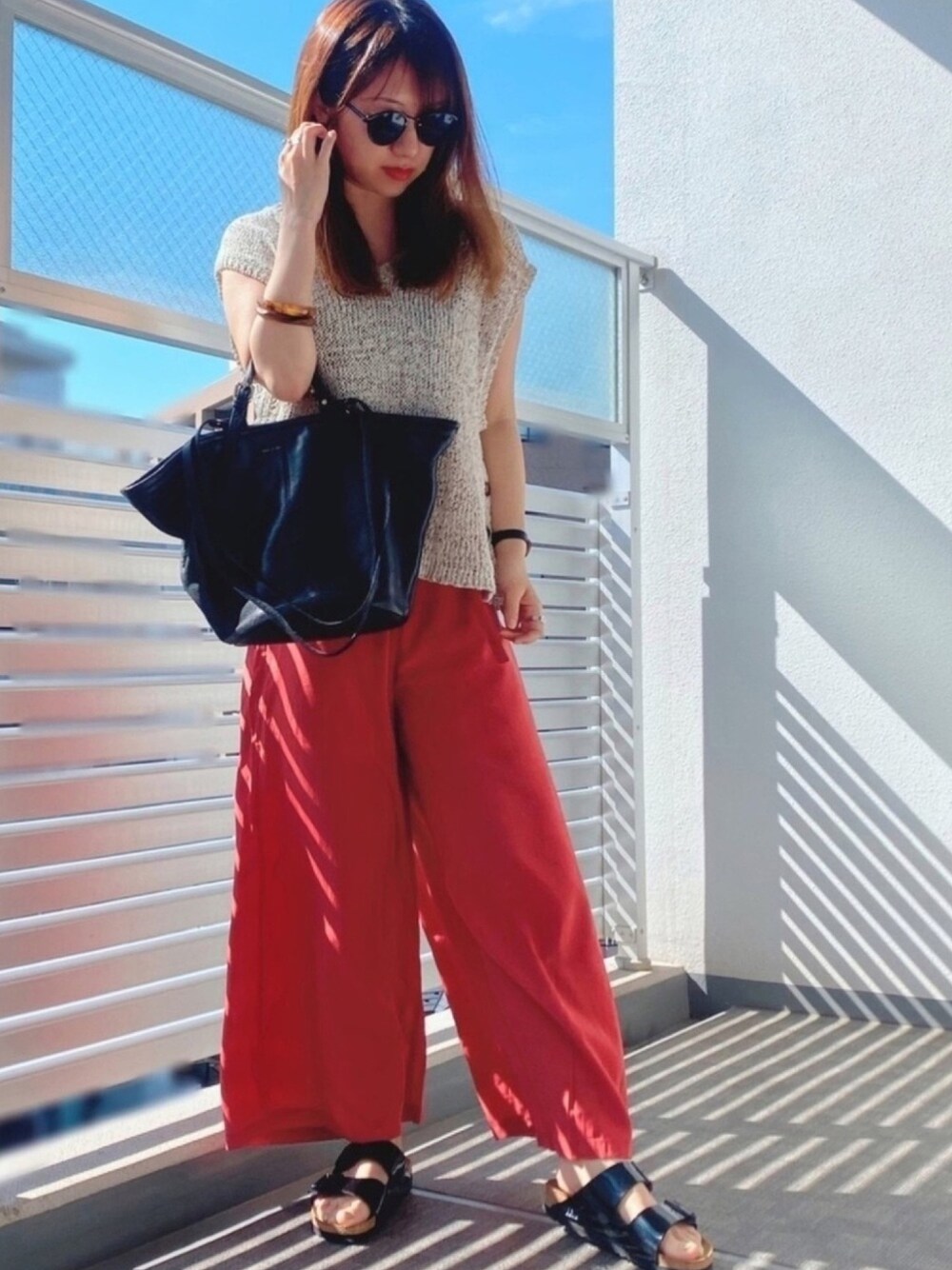 オレンジ系のその他パンツ、ブラック系のサンダル、ブラウン系のTシャツ/カットソーを着用したレディースの春コーディネートの1枚目の写真