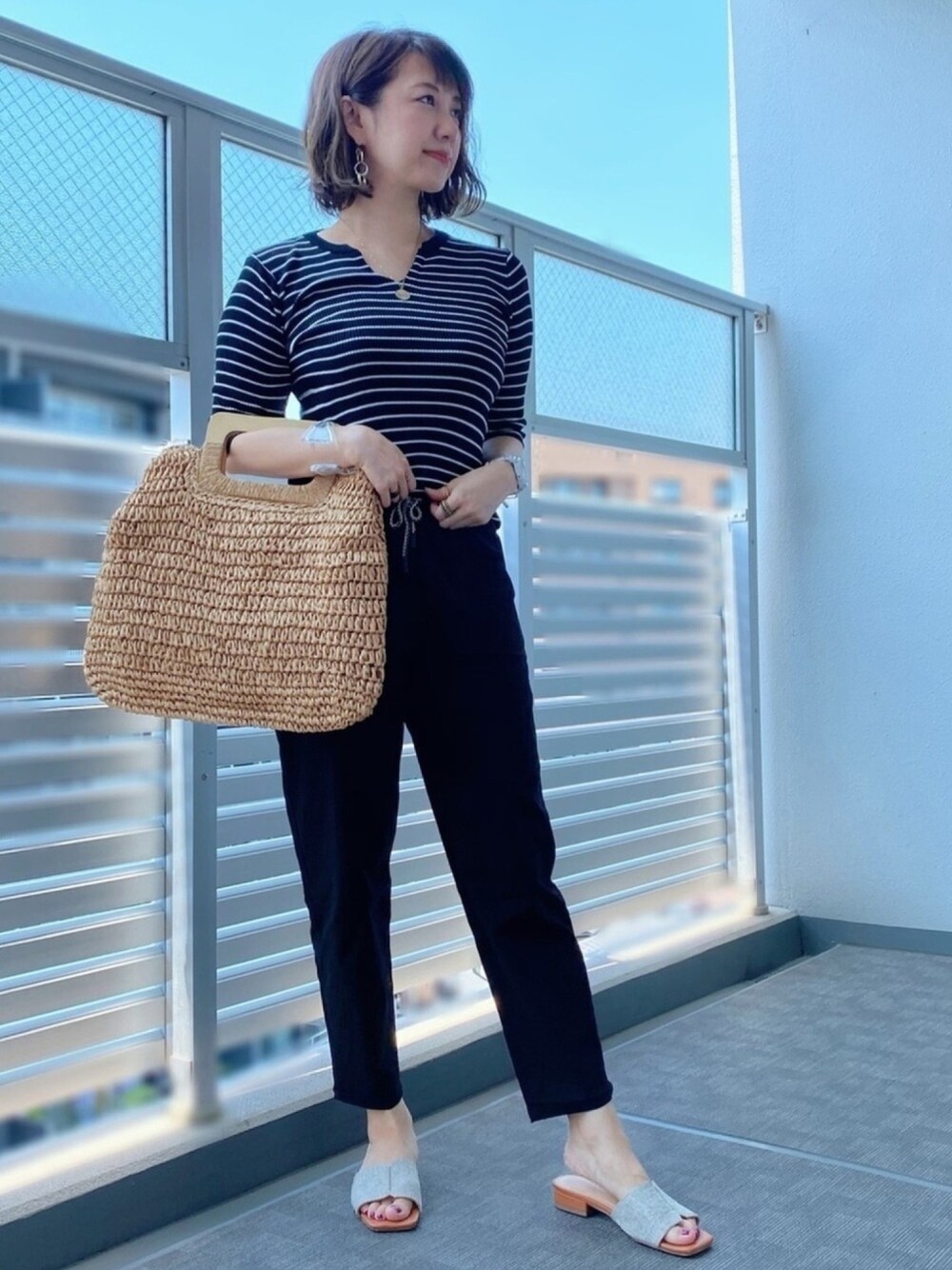 ブラック系のパンツ、ベージュ系のバッグ、ブラック系のTシャツ/カットソーを着用したレディースの夏コーディネートの1枚目の写真