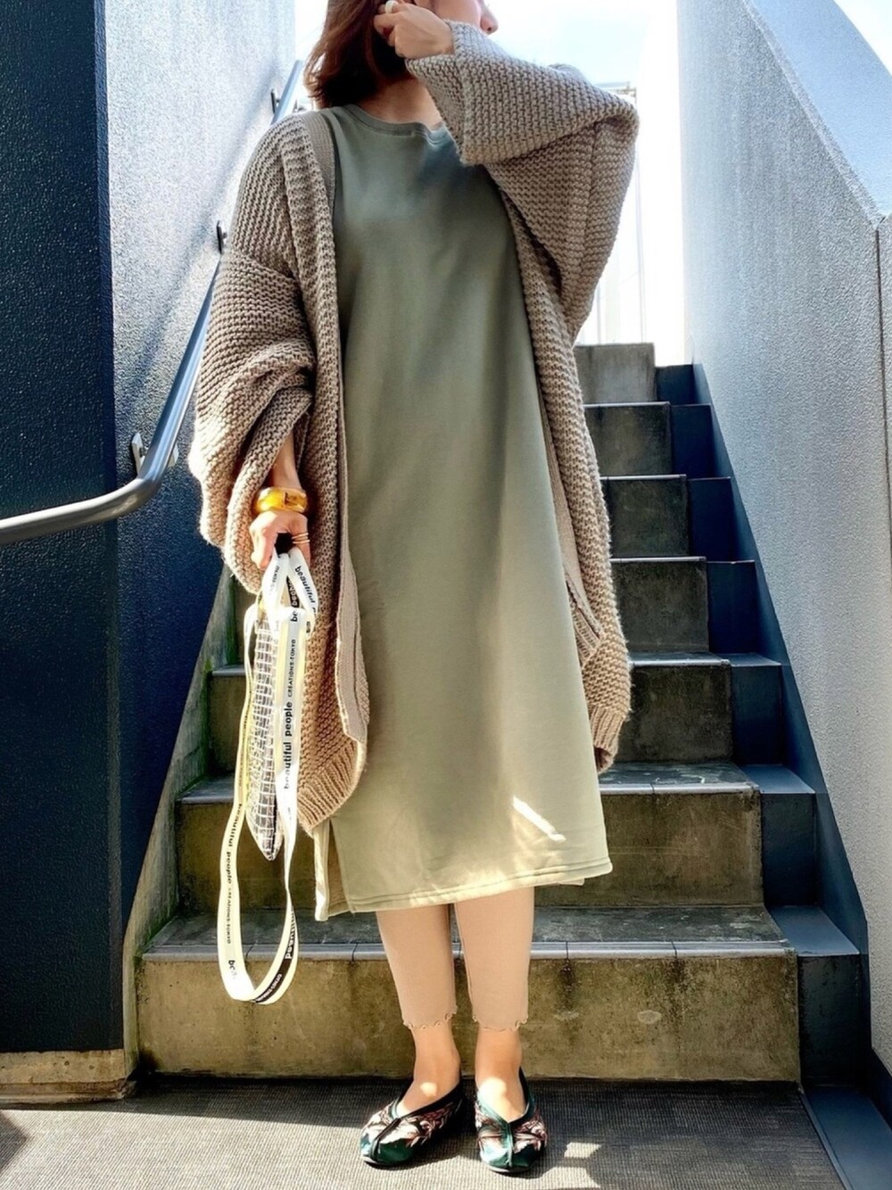 グリーン系のワンピース/ドレス、ベージュ系のカーディガン/ボレロ、ブラック系のショルダーバッグを着用したレディースの秋コーディネートの1枚目の写真