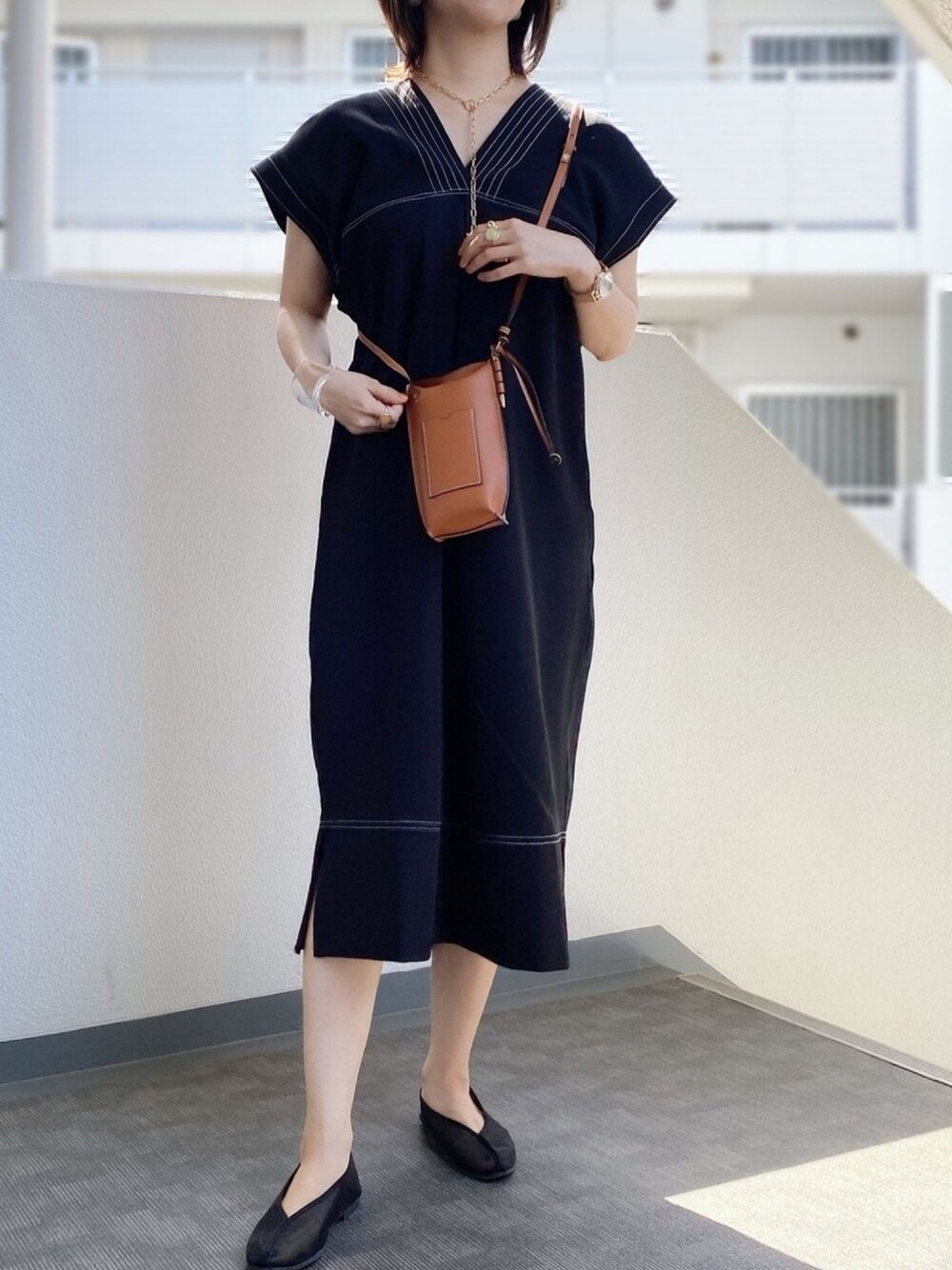 ブラック系のワンピース、ブラック系のバレエシューズ、ブラウン系のショルダーバッグを着用したレディースの春コーディネートの1枚目の写真