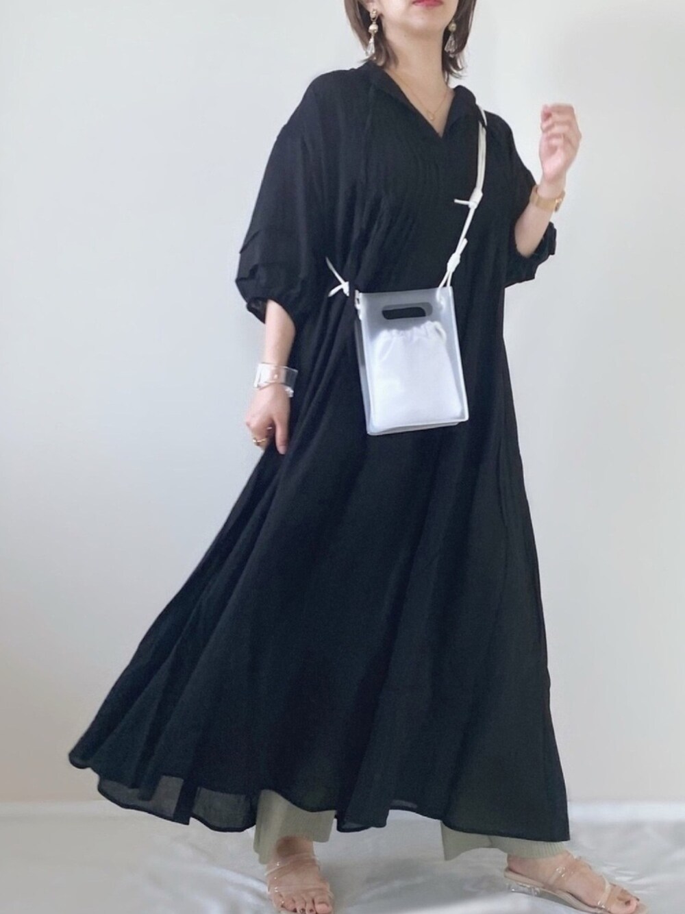 ブラック系のワンピース、ベージュ系のサンダル、ホワイト系のショルダーバッグを着用したレディースの春コーディネートの1枚目の写真