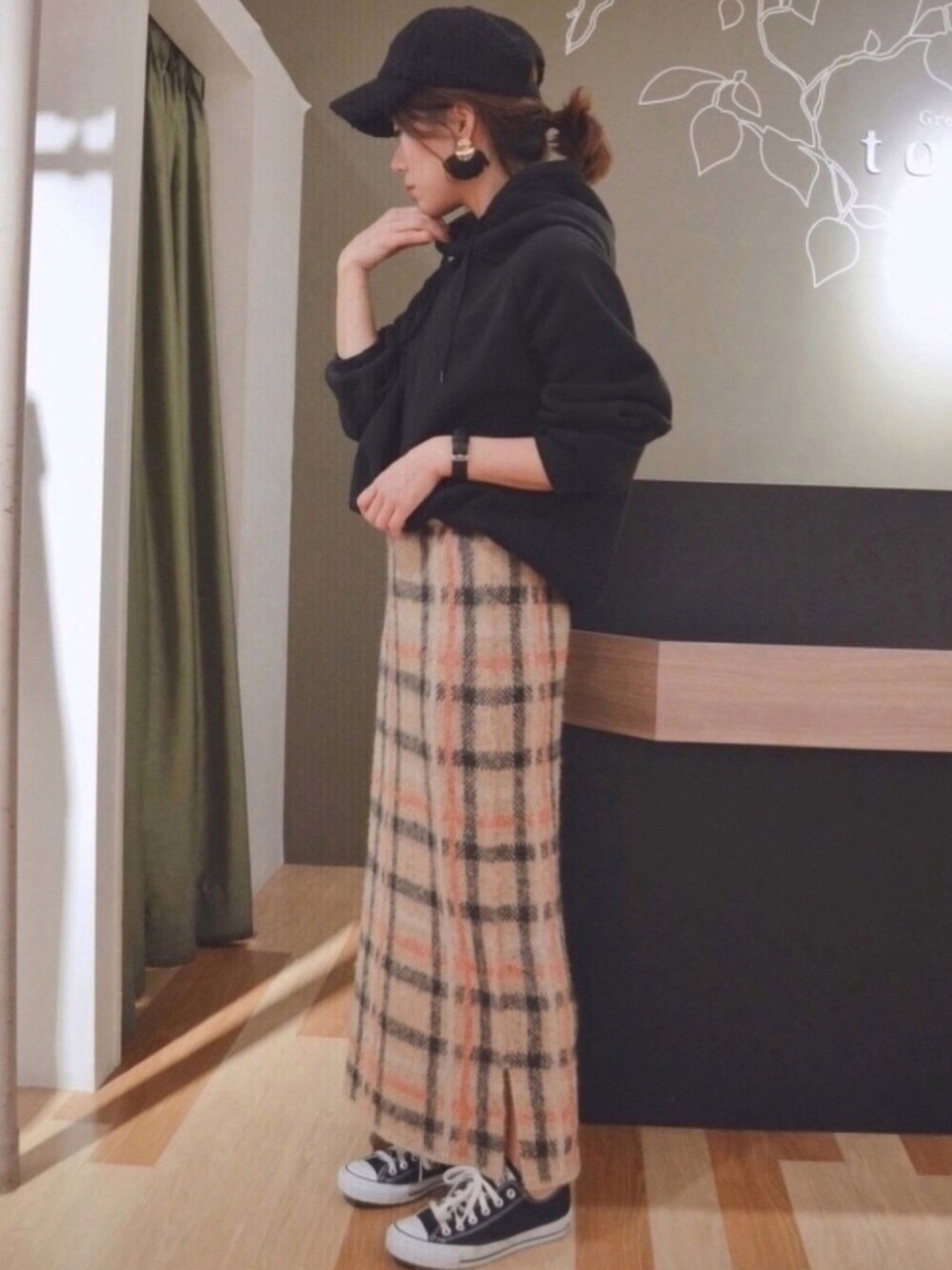 ベージュ系のスカート、ブラック系のパーカー、ブラック系のブルゾンを着用したレディースの冬コーディネートの1枚目の写真