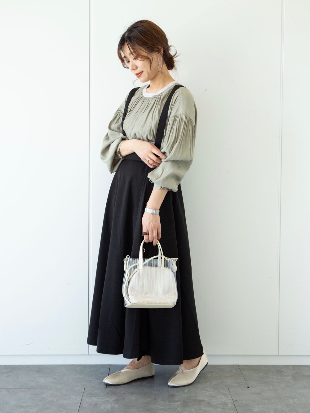 ブラック系のTシャツ/カットソー、ベージュ系のジャンパースカート、ホワイト系のパンプスを着用したレディースの春コーディネートの1枚目の写真