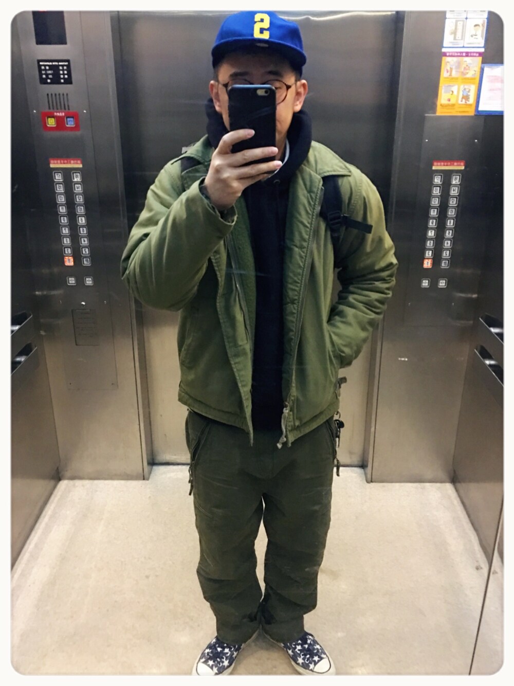 ブラック系のスウェット、グリーン系のチノパンツ、ブルー系のスニーカーを着用したメンズの冬コーディネートの1枚目の写真