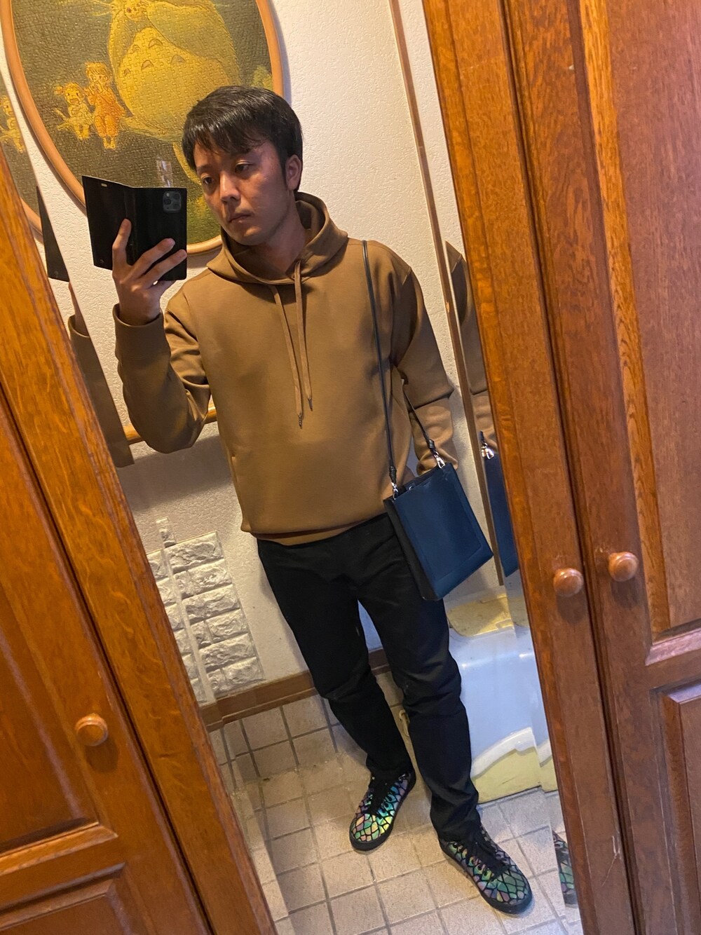 ブラウン系のパーカー、ブラック系のパンツ、ブラック系のショルダーバッグを着用したメンズの秋コーディネートの1枚目の写真