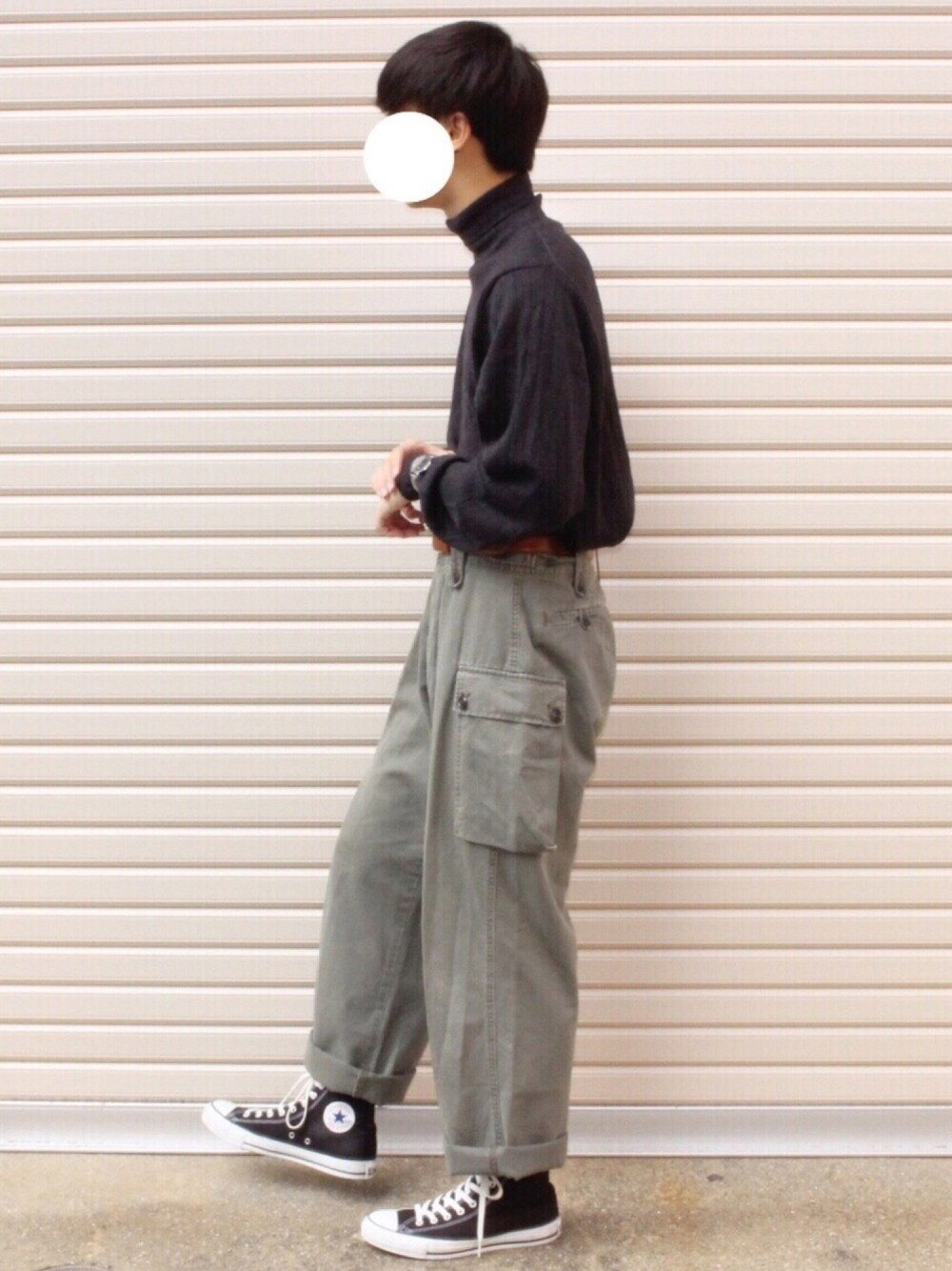 ブラック系のトップス、グリーン系のカーゴパンツ、ブラック系のスニーカーを着用したメンズの秋コーディネートの1枚目の写真