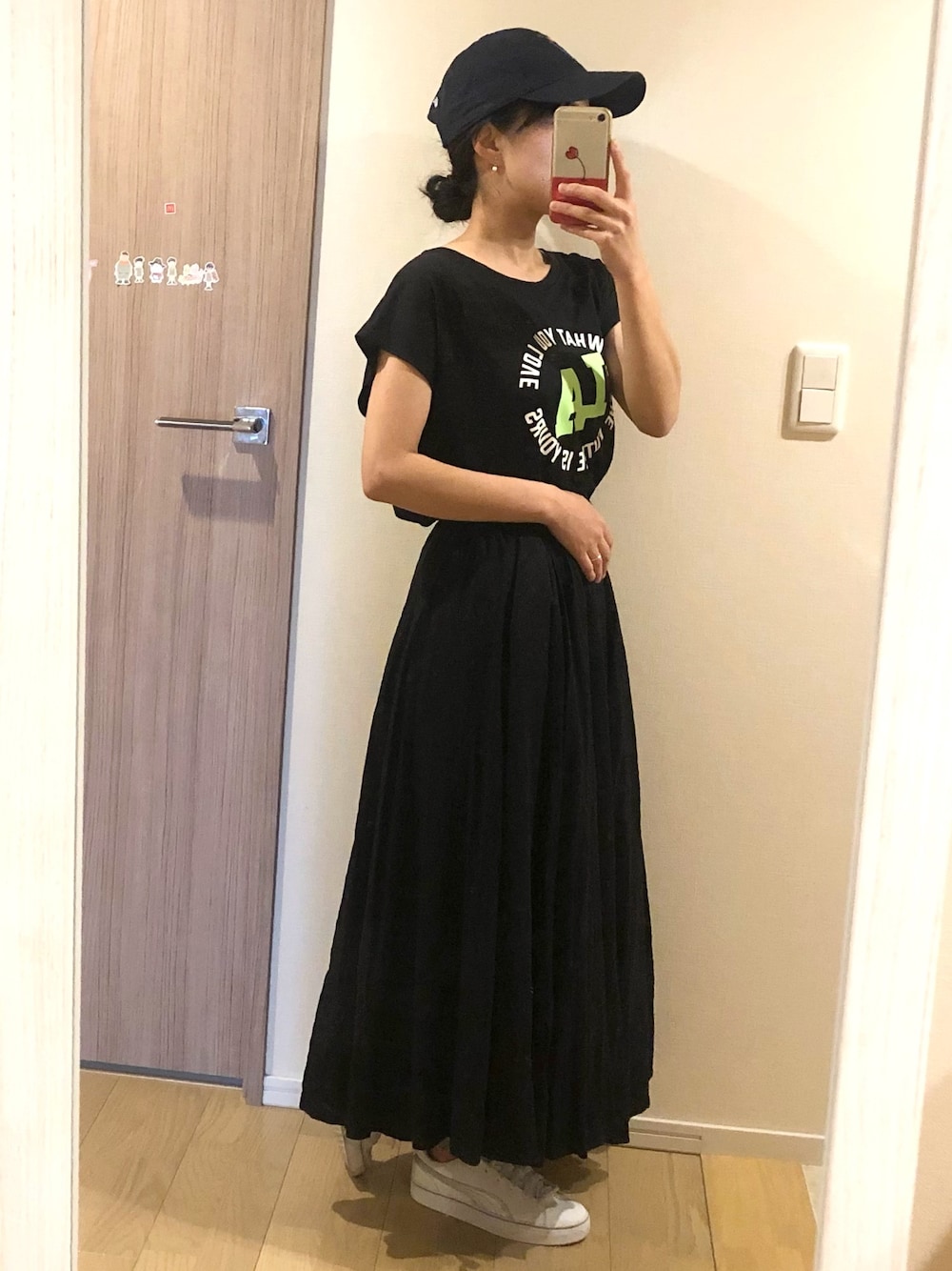 ブラック系のTシャツ/カットソー、ブラック系のスカート、ホワイト系のスニーカーを着用したレディースの春コーディネートの1枚目の写真