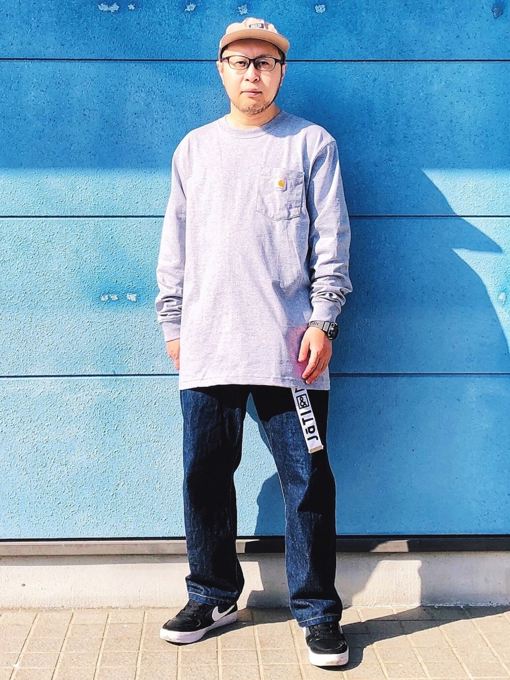 グレー系のTシャツ/カットソー、ブルー系のデニムパンツ、ブラック系のスニーカーを着用したメンズの春コーディネートの1枚目の写真