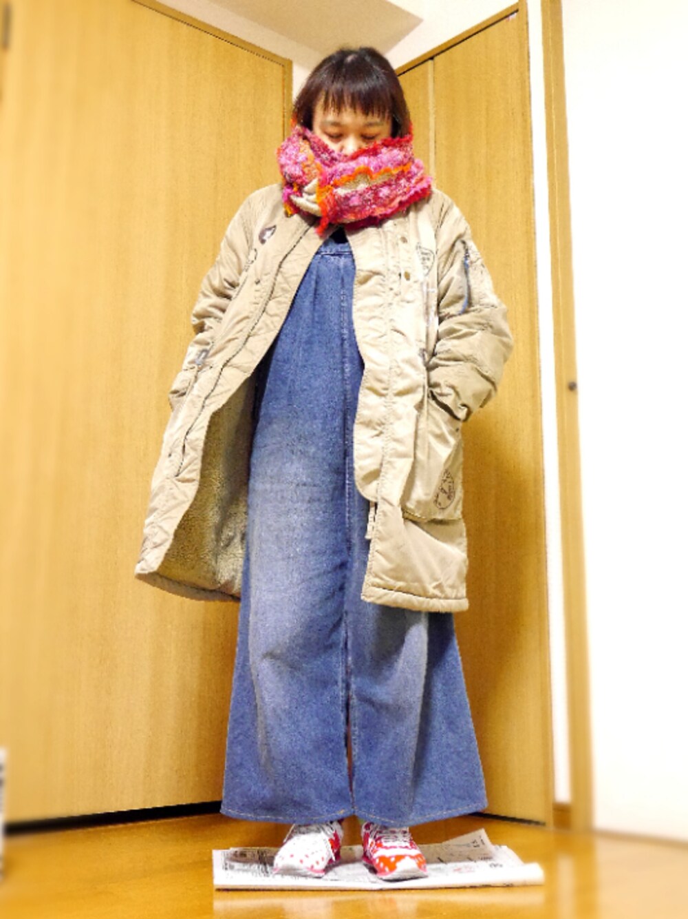 ベージュ系のミリタリージャケット、ブルー系のサロペット/オーバーオール、レッド系のスニーカーを着用したレディースの冬コーディネートの1枚目の写真