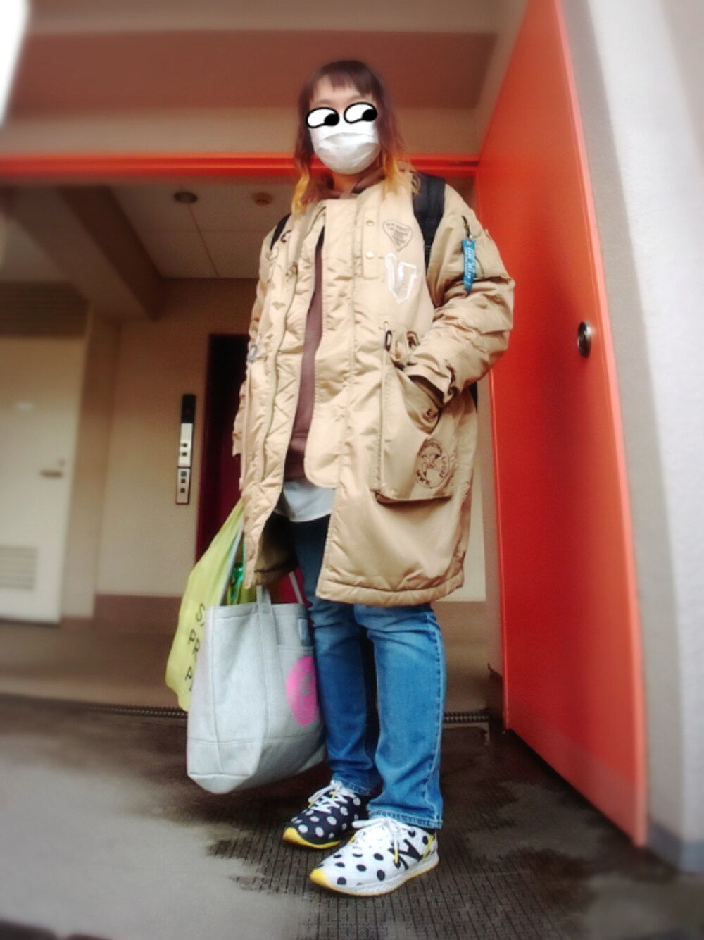 ベージュ系のミリタリージャケット、ブルー系のデニムパンツ、ブラウン系のパーカーを着用したレディースの冬コーディネートの1枚目の写真