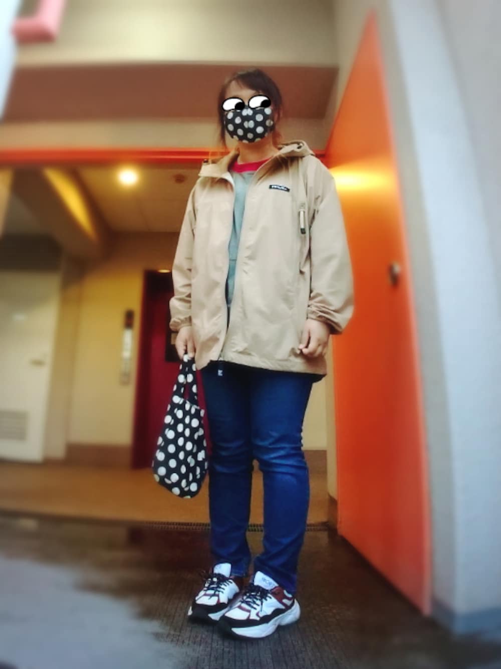 ベージュ系のナイロンジャケット、ホワイト系のスニーカー、ブルー系のデニムパンツを着用したレディースの春コーディネートの1枚目の写真