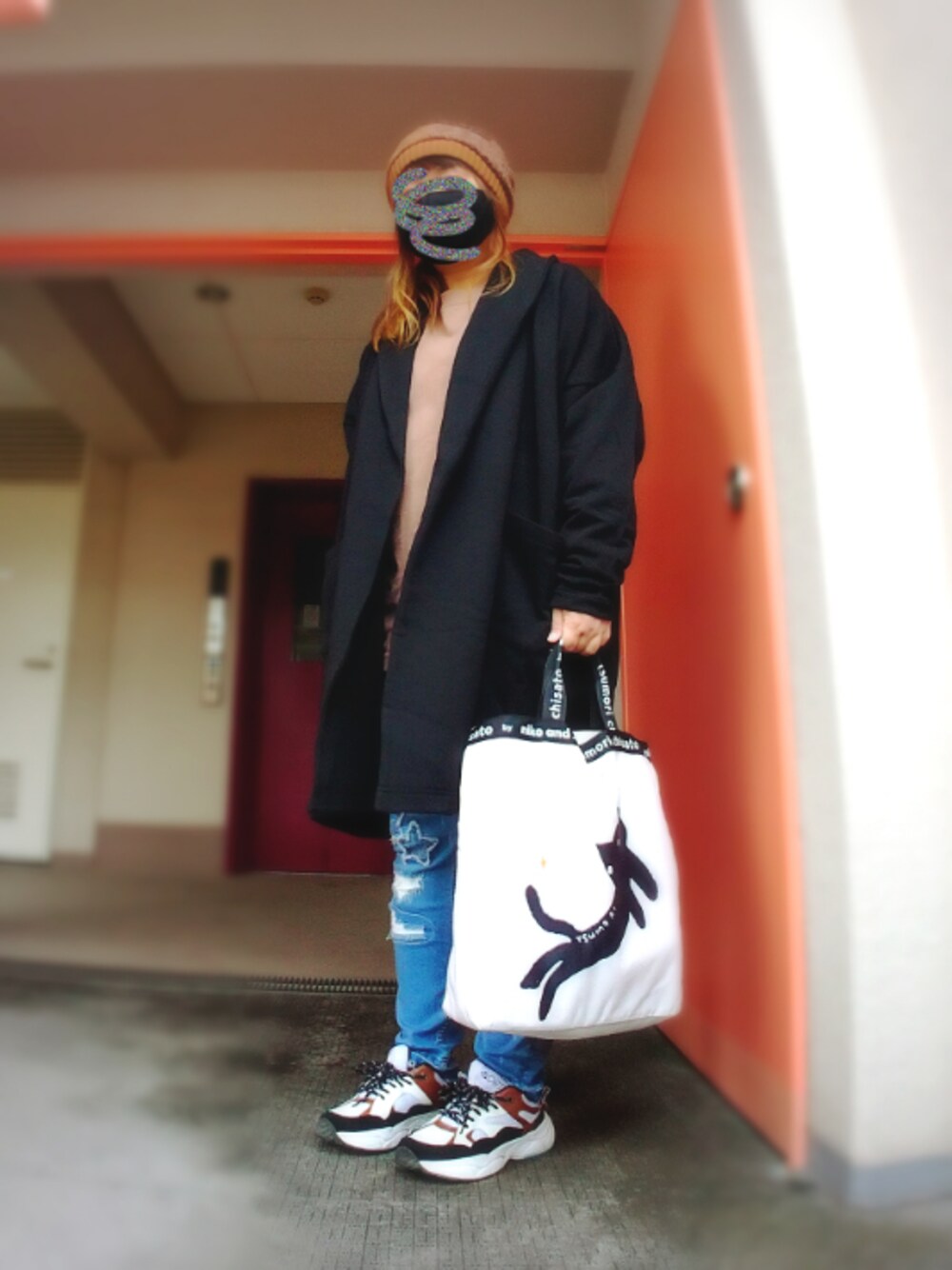 ブラック系のカーディガン/ボレロ、オレンジ系のTシャツ/カットソー、ブルー系のデニムパンツを着用したレディースの秋コーディネートの1枚目の写真