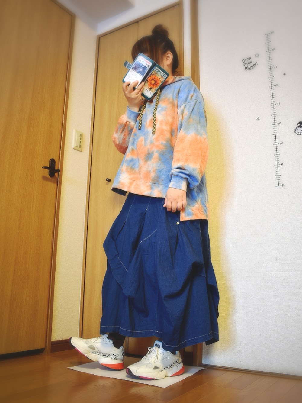 ブルー系のデニムスカート、ブルー系のパーカー、ホワイト系のスニーカーを着用したレディースの春コーディネートの1枚目の写真