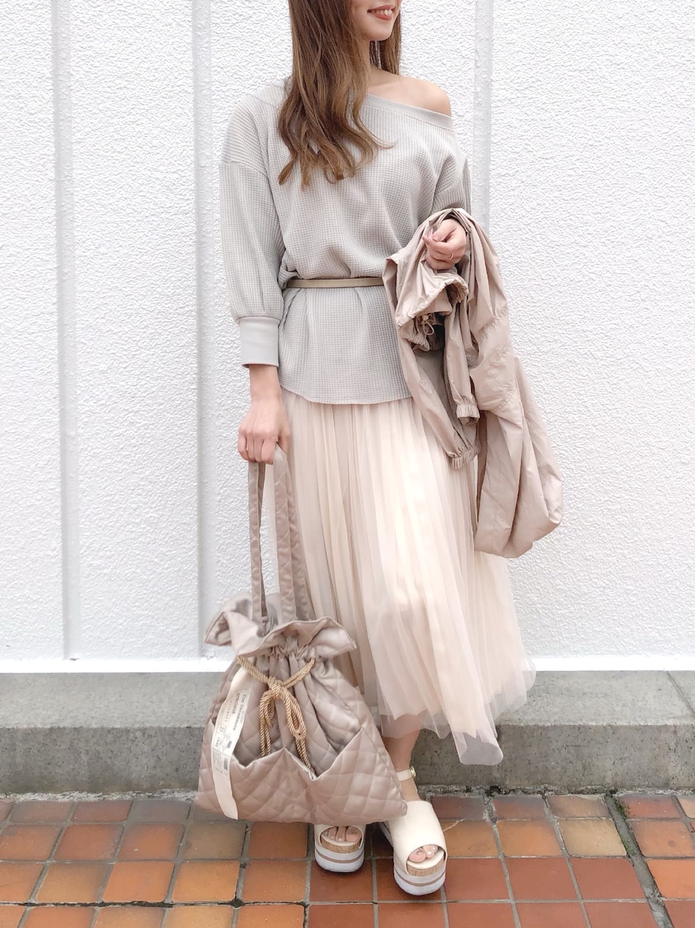 ホワイト系のスカート、ベージュ系のマウンテンパーカー、ベージュ系のトートバッグを着用したレディースの春コーディネートの1枚目の写真