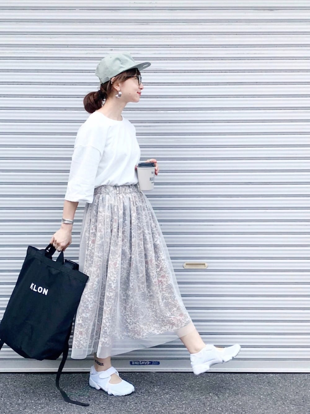 ホワイト系のTシャツ/カットソー、ホワイト系のスカート、ホワイト系のサンダルを着用したレディースの春コーディネートの1枚目の写真