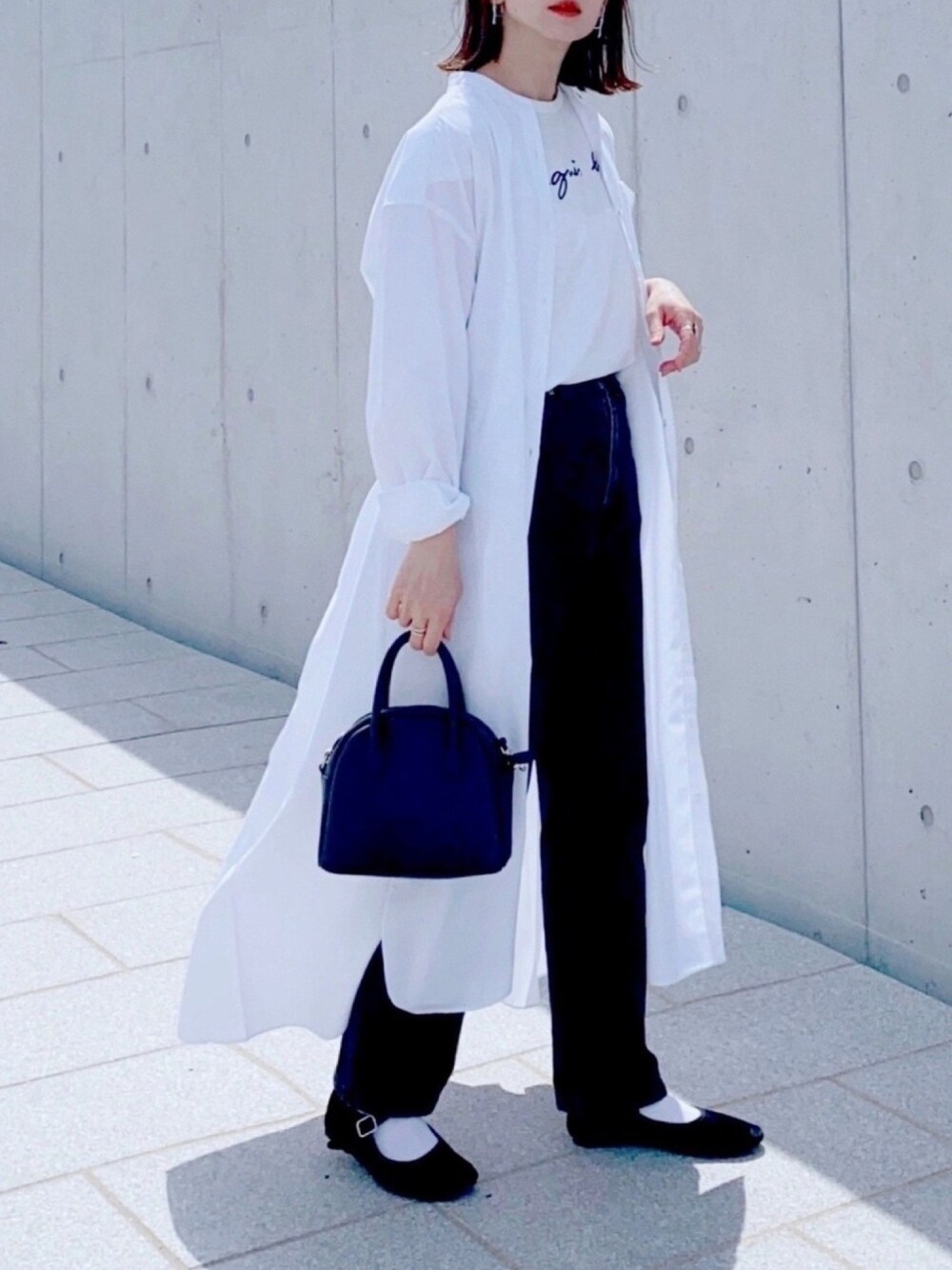 ホワイト系のワンピース、ブラック系のデニムパンツ、ブラック系のショルダーバッグを着用したレディースの春コーディネートの1枚目の写真