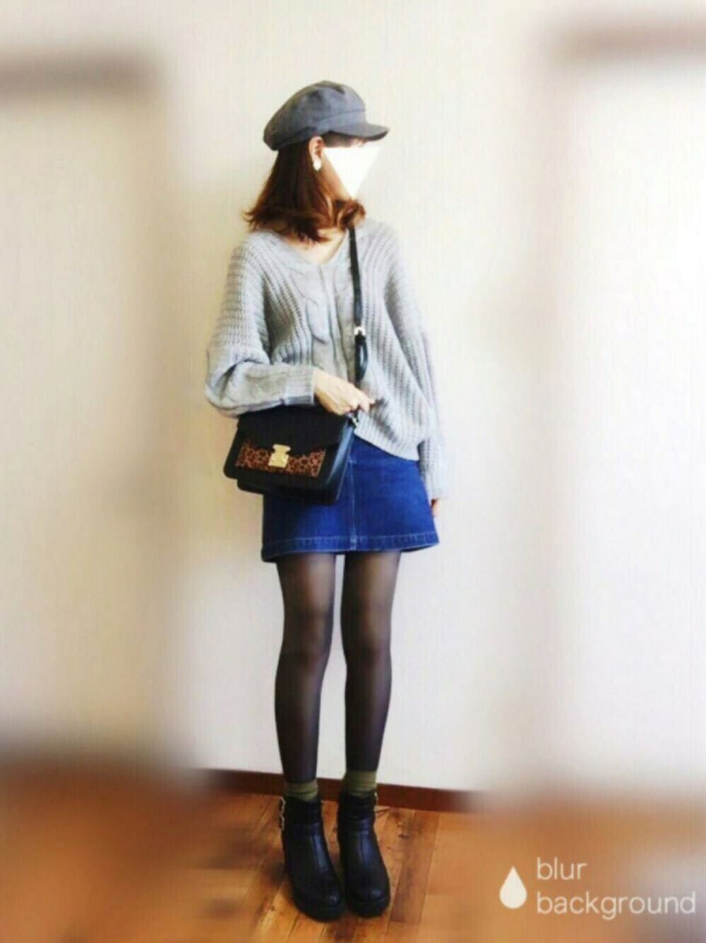 グレー系のニット/セーター、ブルー系のデニムスカート、ブラック系のブーツを着用したレディースの秋コーディネートの1枚目の写真