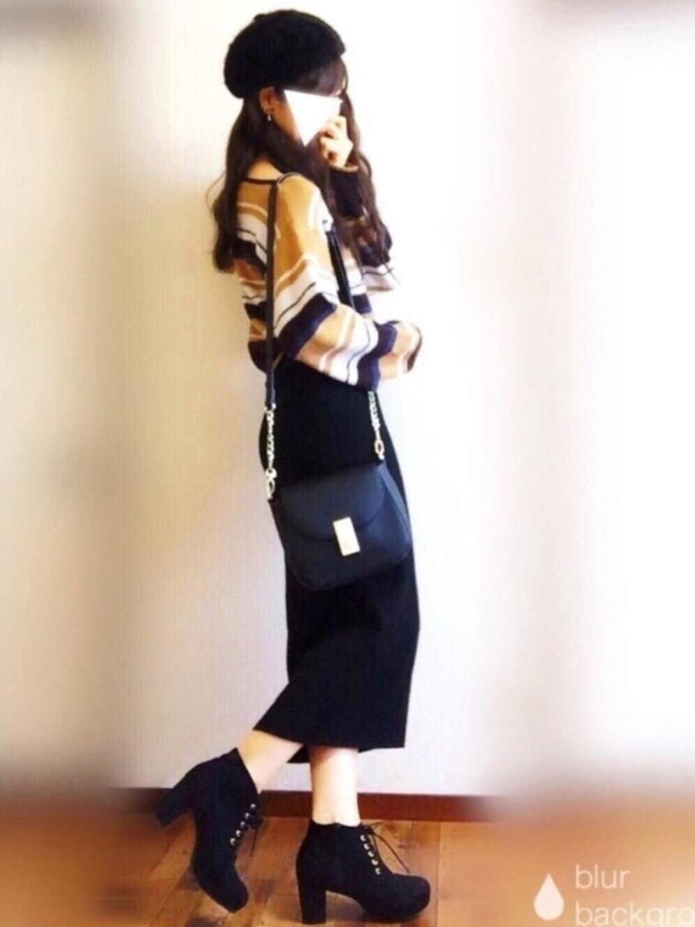 イエロー系のニット/セーター、ブラック系のスカート、ブラック系のショルダーバッグを着用したレディースの冬コーディネートの1枚目の写真