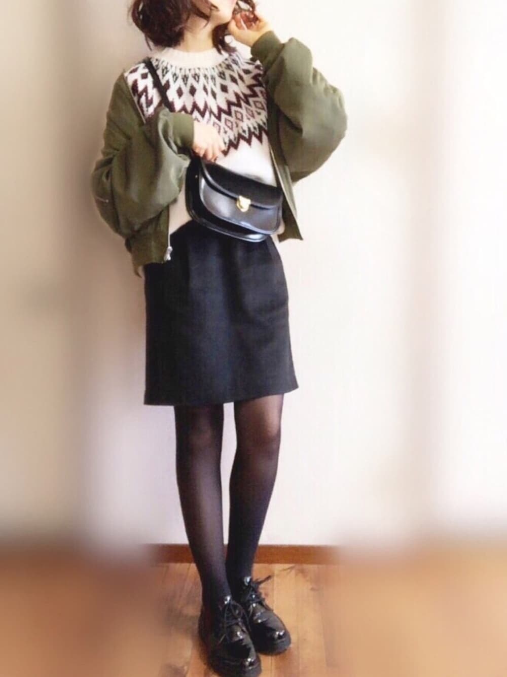 グリーン系のMA-1、ホワイト系のニット/セーター、ブラック系のスカートを着用したレディースの冬コーディネートの1枚目の写真